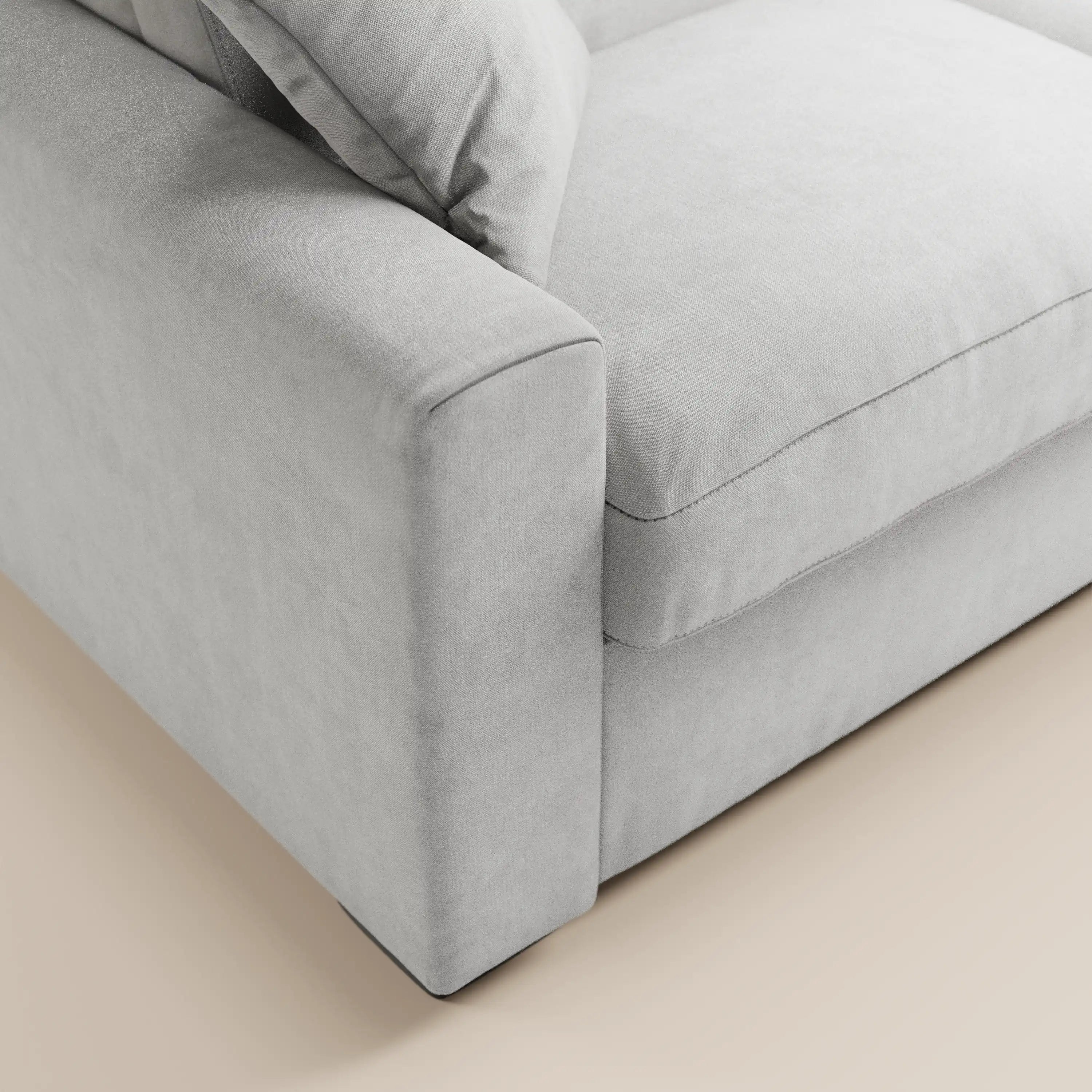 Primo piano del divano letto Maximus a 3 posti con materasso ALTO 20 cm di Divani.Store, caratterizzato da un tessuto grigio chiaro Oeko-Tex antimacchia, poggiatesta reclinabili e un design minimalista. I cuscini dei braccioli, della seduta e dello schienale sono ripresi su uno sfondo beige.