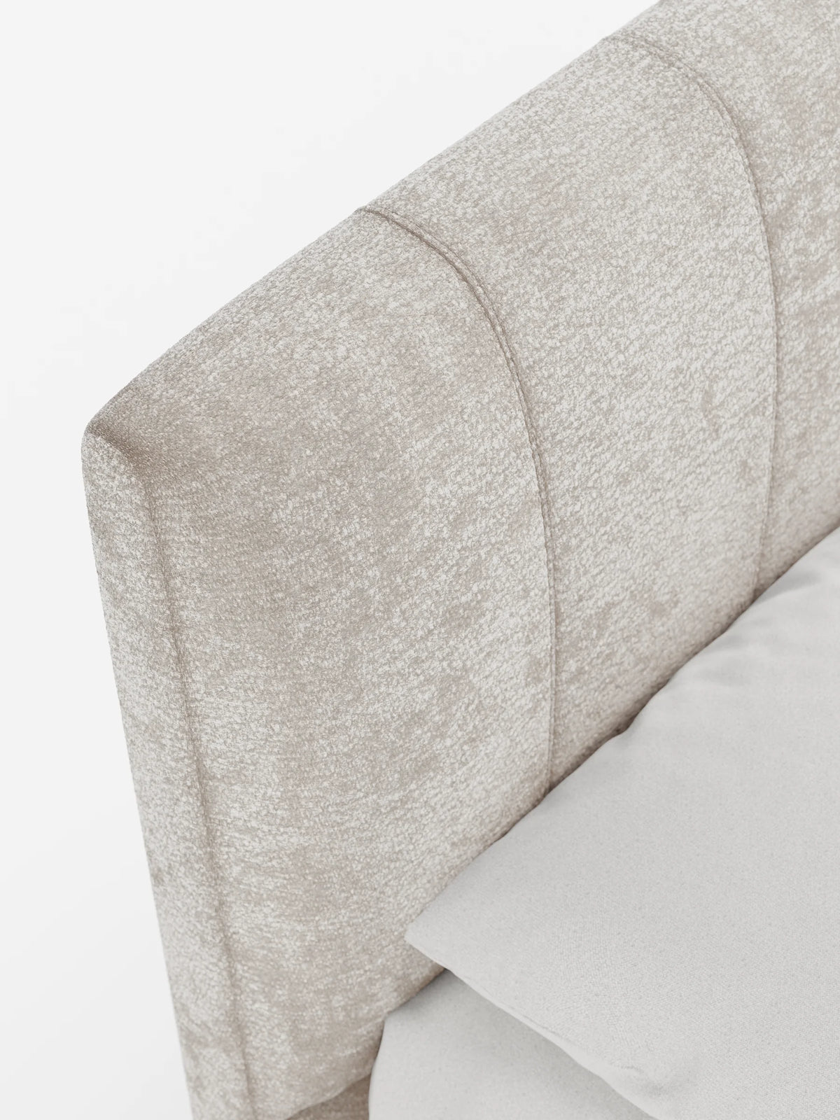 Un primo piano ripreso da un'angolazione dall'alto mostra il letto imbottito ONYX con contenitore e testiera verticale in tessuto certificato Oeko-Tex® con trapuntatura a canali verticali, adagiato su un lenzuolo liscio di colore grigio chiaro su uno sfondo bianco a tinta unita.