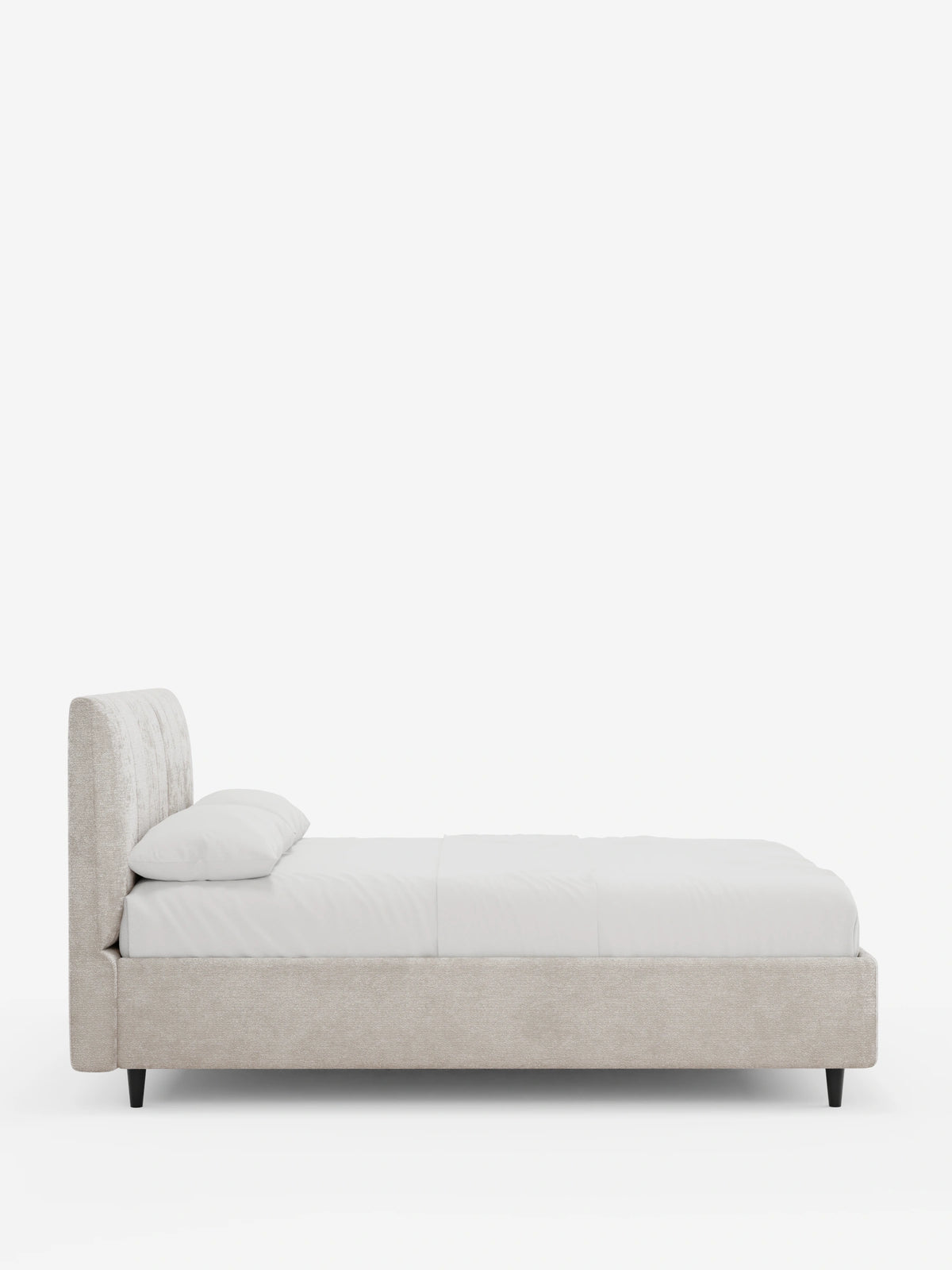 Vista laterale di un letto imbottito ONYX con contenitore e testiera verticale in tessuto certificato Oeko-Tex® color beige chiaro, caratterizzato da un’alta testiera a pannelli verticali e da una struttura bassa su sottili gambe scure, con biancheria da letto bianca.