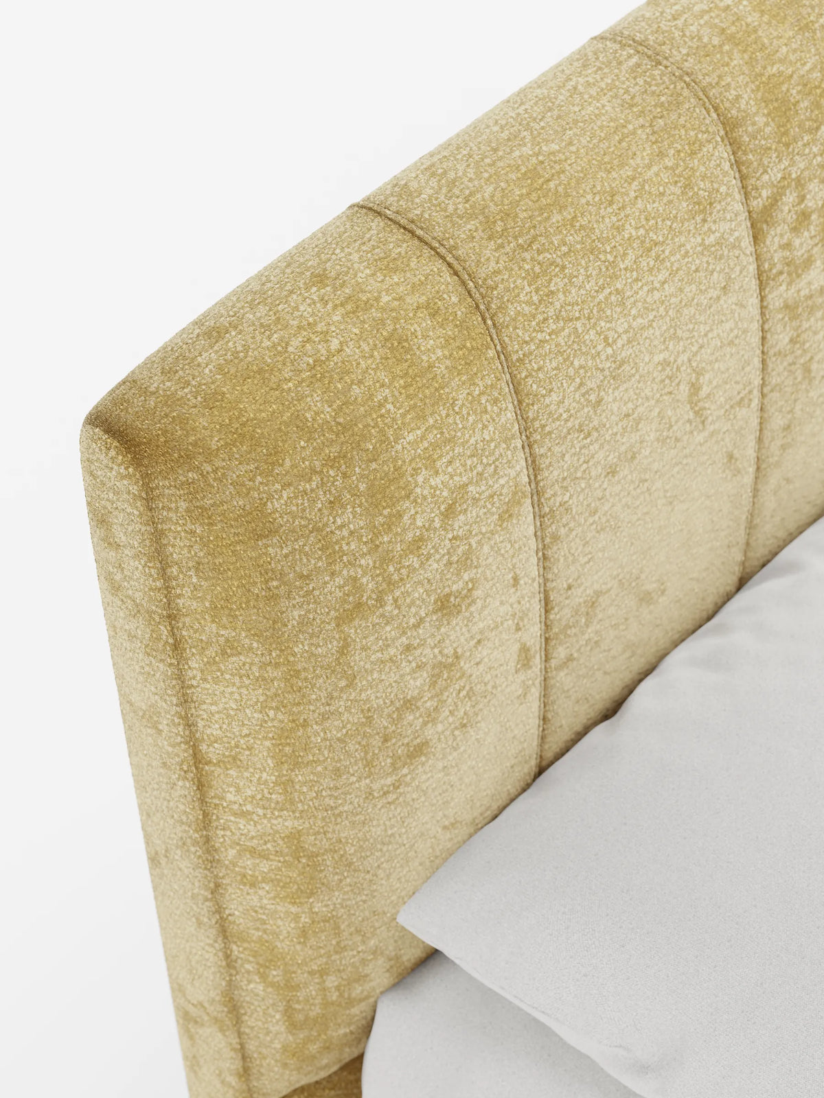 Primo piano obliquo della testiera verticale cucita di colore giallo senape del letto imbottito ONYX con vano contenitore e testiera verticale in tessuto certificato Oeko-Tex®, in primo piano su un cuscino grigio chiaro su sfondo bianco.