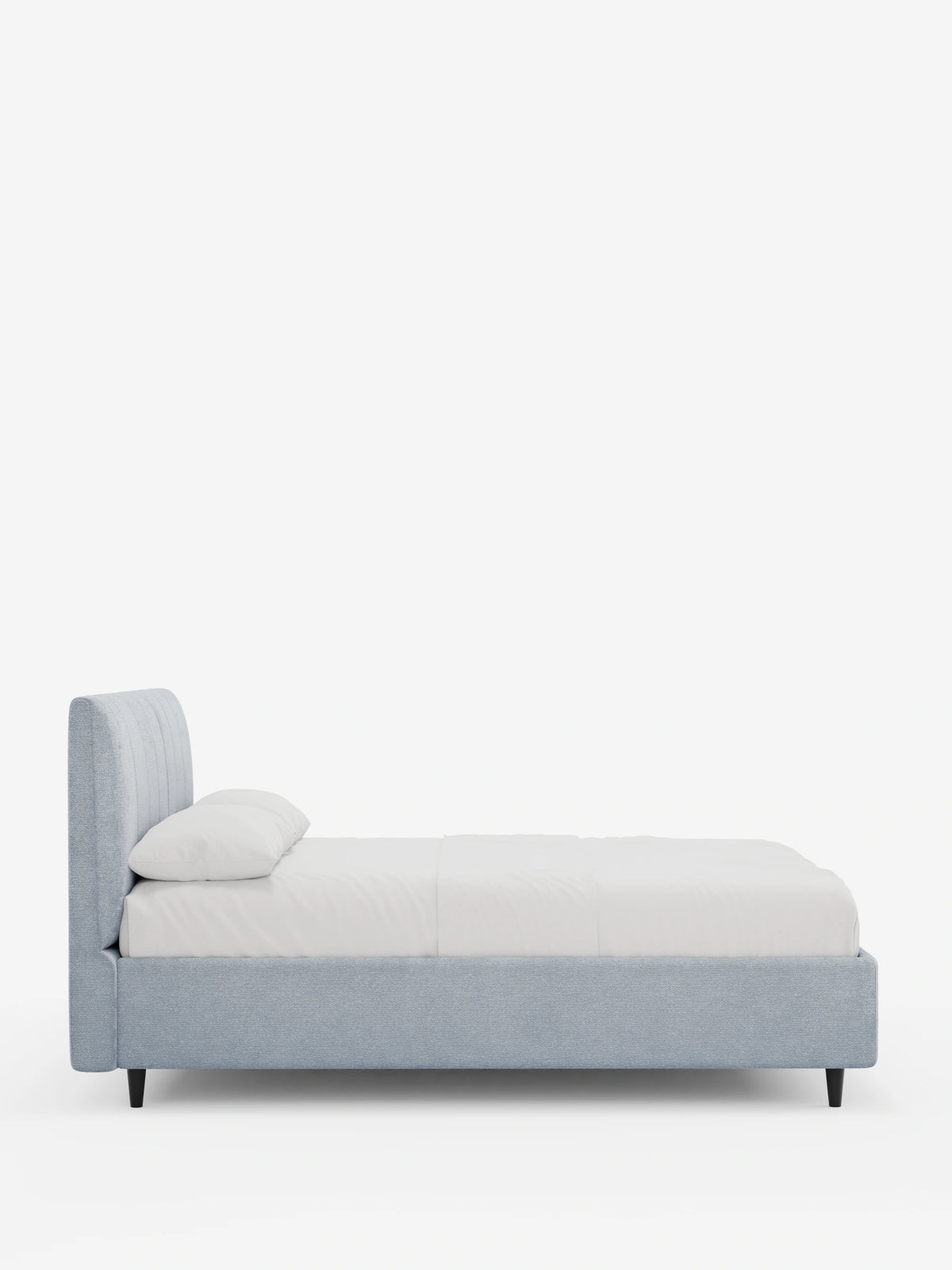 Vista laterale di un letto imbottito ONYX con contenitore e testiera verticale in tessuto certificato Oeko-Tex® di colore azzurro, caratterizzato da un'alta testiera a pannelli verticali, biancheria da letto bianca e piedini scuri su uno sfondo bianco a tinta unita.