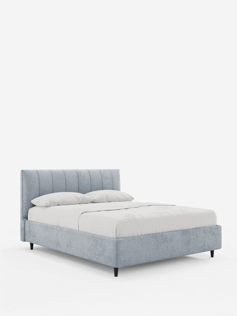 Il letto imbottito ONYX con contenitore e testiera verticale in tessuto certificato Oeko-Tex® è un letto moderno di colore azzurro, caratterizzato da una testiera alta con cuciture verticali, biancheria da letto di un bianco brillante e gambe scure affusolate su sfondo bianco.