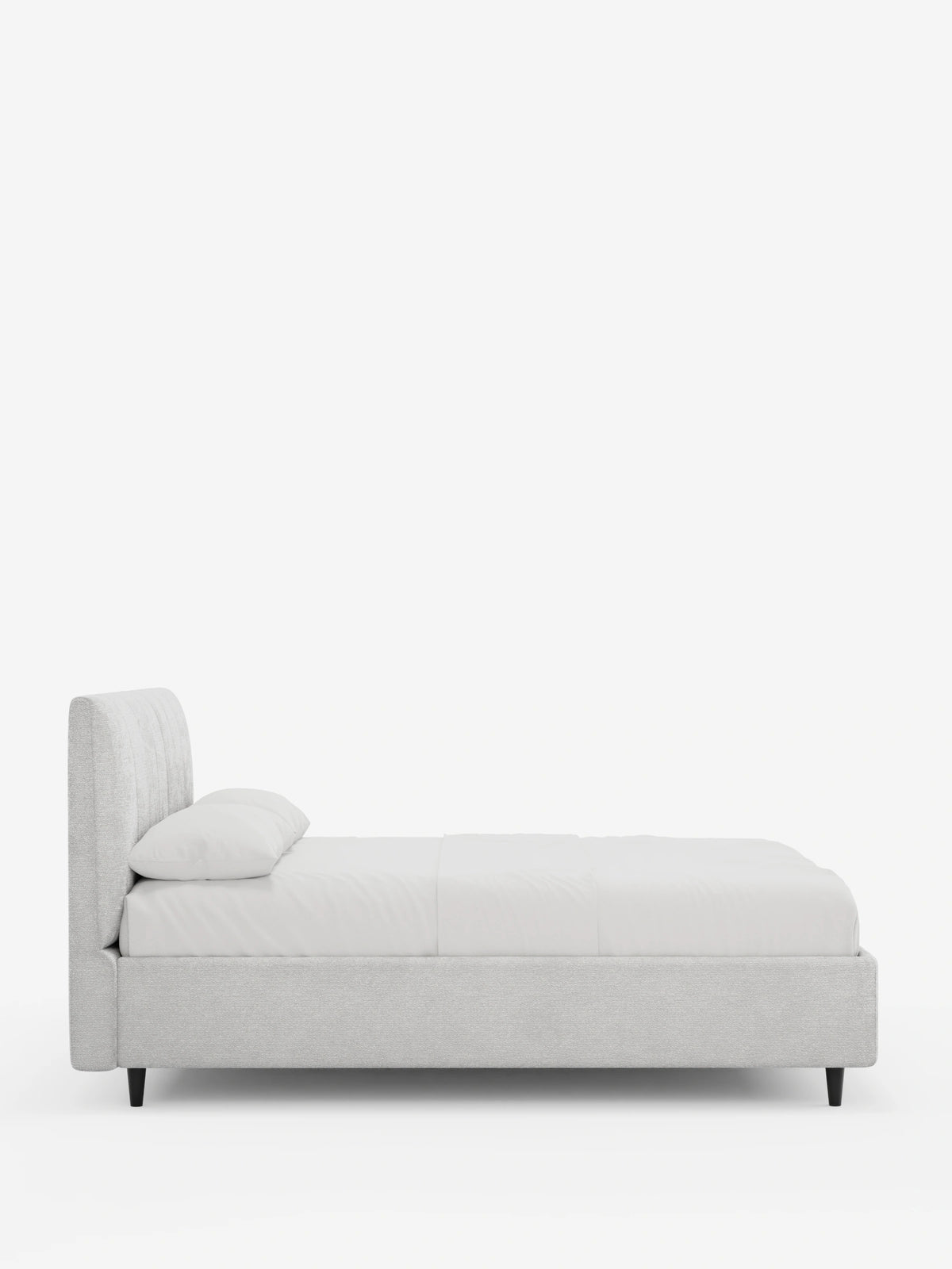 Una vista laterale del letto imbottito ONYX con contenitore e testiera verticale in tessuto certificato Oeko-Tex®: un letto moderno di colore grigio chiaro con una testiera alta a pannelli verticali, lenzuola bianche e gambe coniche scure su sfondo bianco.