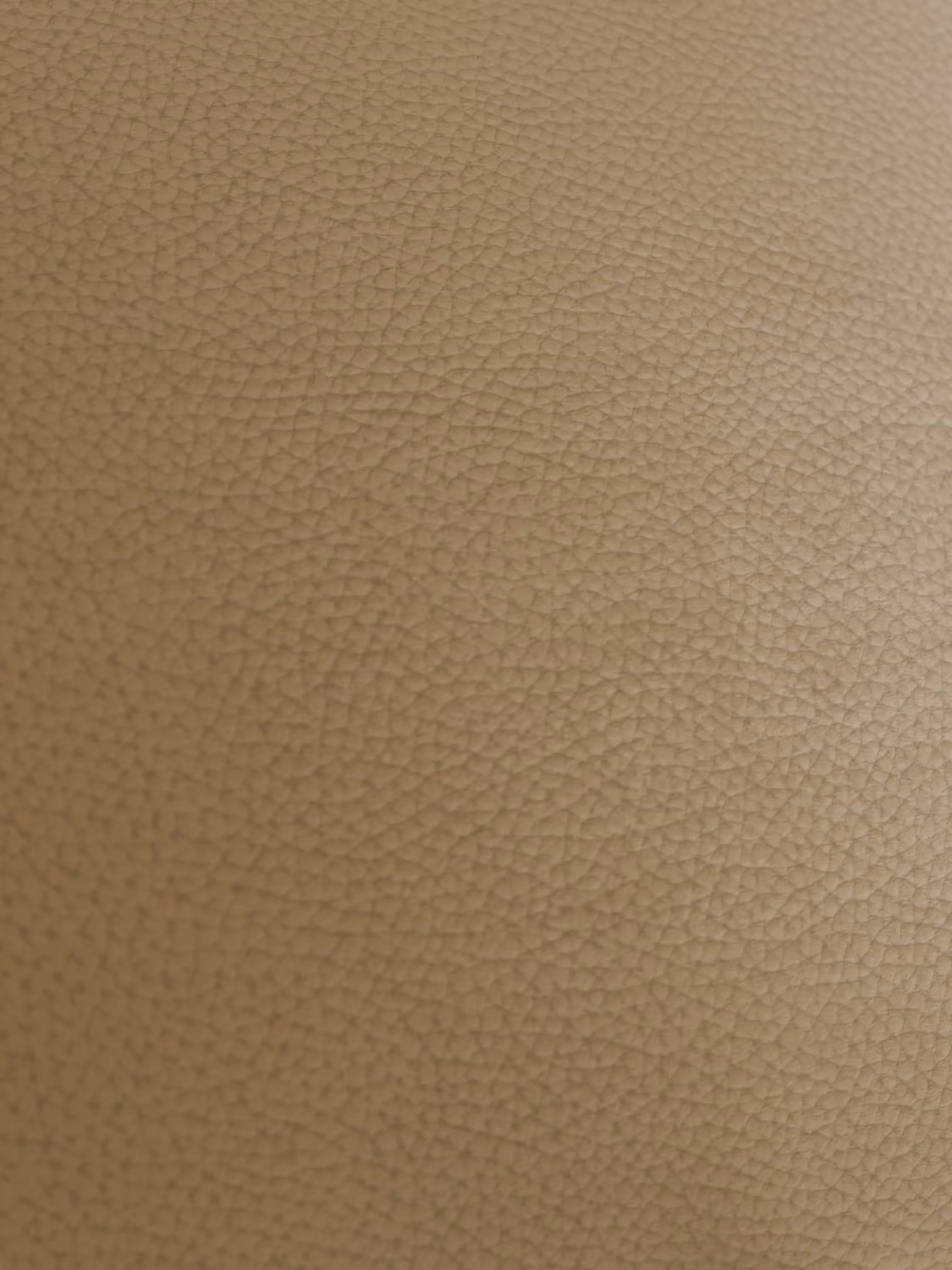 Primo piano della superficie in vera pelle marrone chiaro del divano Chester 4 Posti 3 sedute in Vera Pelle – Chesterfield Capitonné Artigianale di Divani.Store, che mostra le raffinate venature della grana e le sottili pieghe naturali. L’illuminazione mette in risalto la caratteristica trama granulosa, creando un aspetto morbido e caldo senza cuciture o segni visibili: una vera testimonianza dell’autentica lavorazione artigianale.