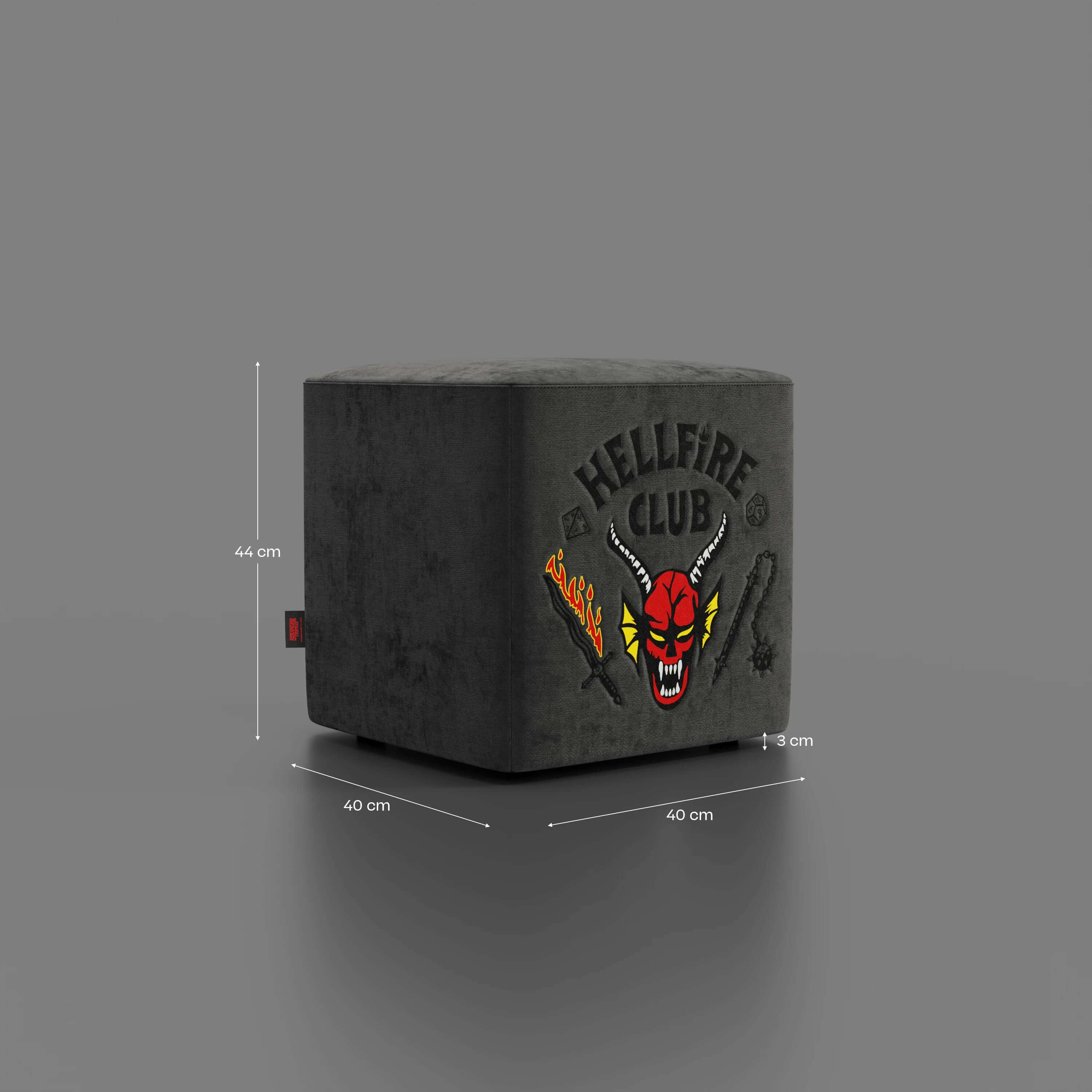 Un Pouf cubo Hellfire Club Stranger Things Edition in antracite di Divani.Store (40x40x44 cm) poggia su un fondo grigio, con il logo e l'artwork "HELLFIRE CLUB". Icona del design in edizione limitata; misure indicate.