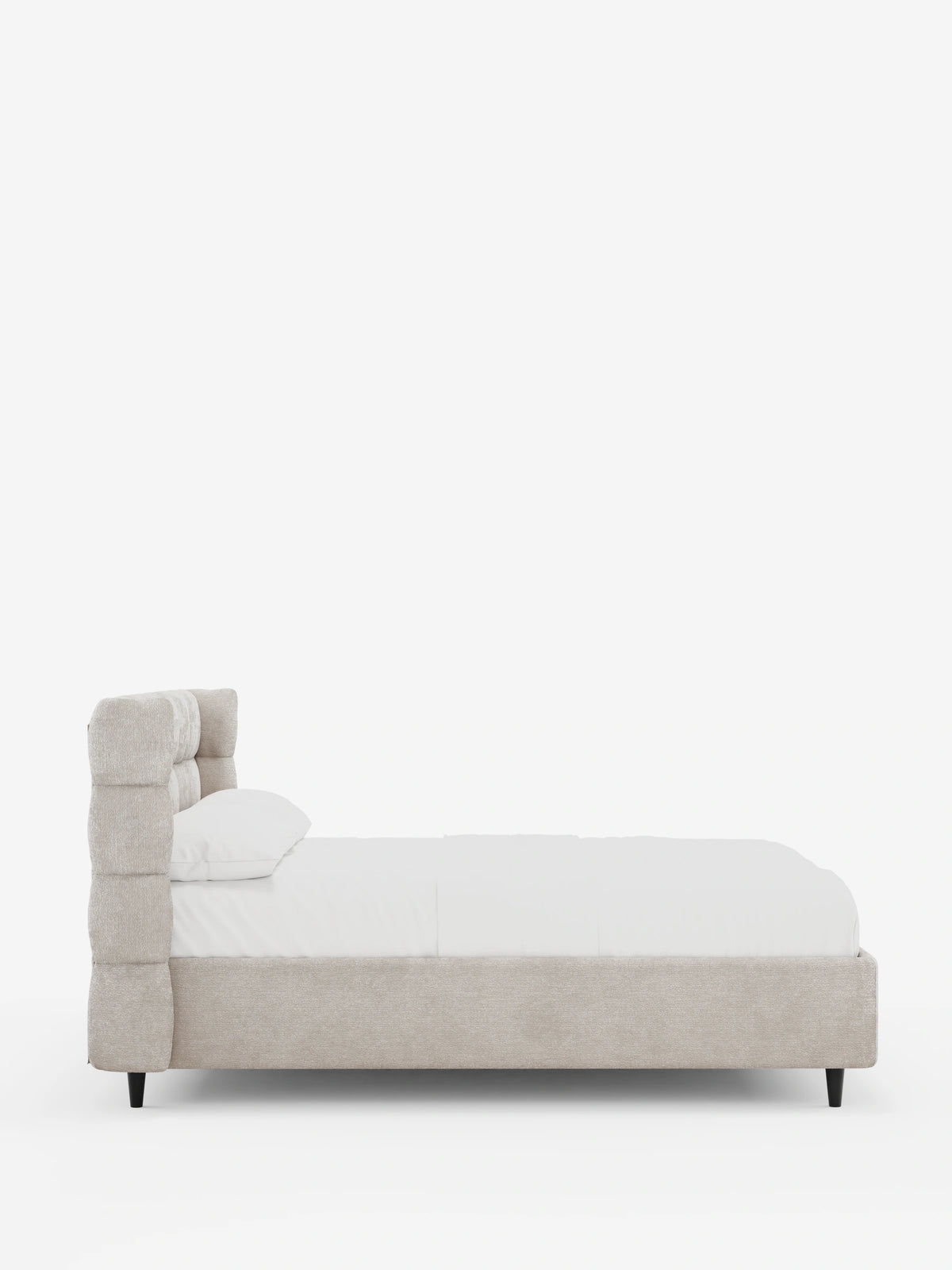 Vista laterale di un letto imbottito RAGNAR color beige con contenitore e testiera capitonné avvolgente, caratterizzato da una testiera alta, biancheria da letto candida e gambe corte, scure e affusolate, su uno sfondo bianco a tinta unita.