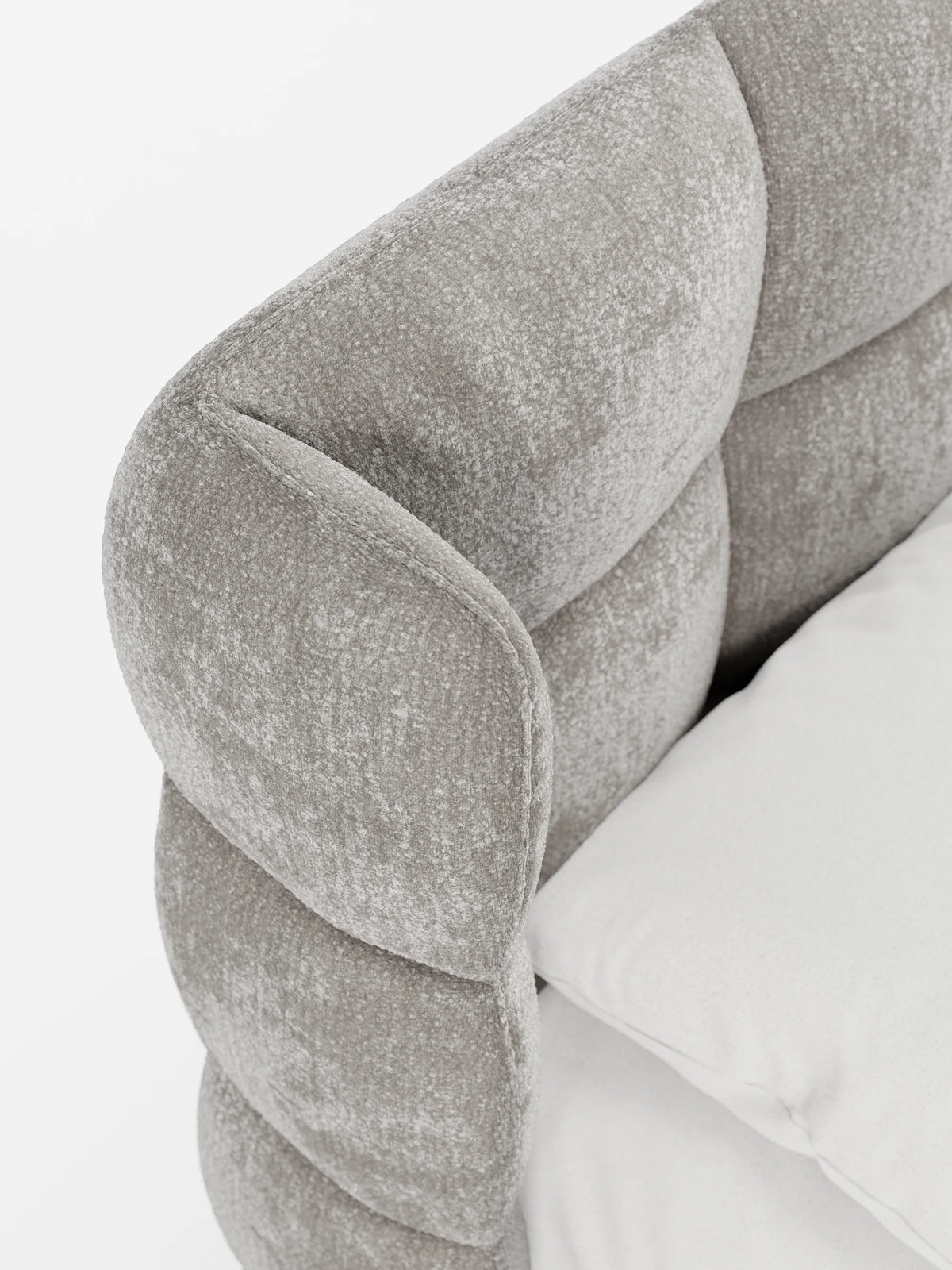 Un primo piano del letto RAGNAR, dalle linee curve e con imbottitura a ciuffetti, dotato di vano contenitore e testiera capitonné avvolgente in tessuto grigio chiaro dalla trama rigata, con una testiera che avvolge il letto, rivestito con lenzuola bianche e immacolate.