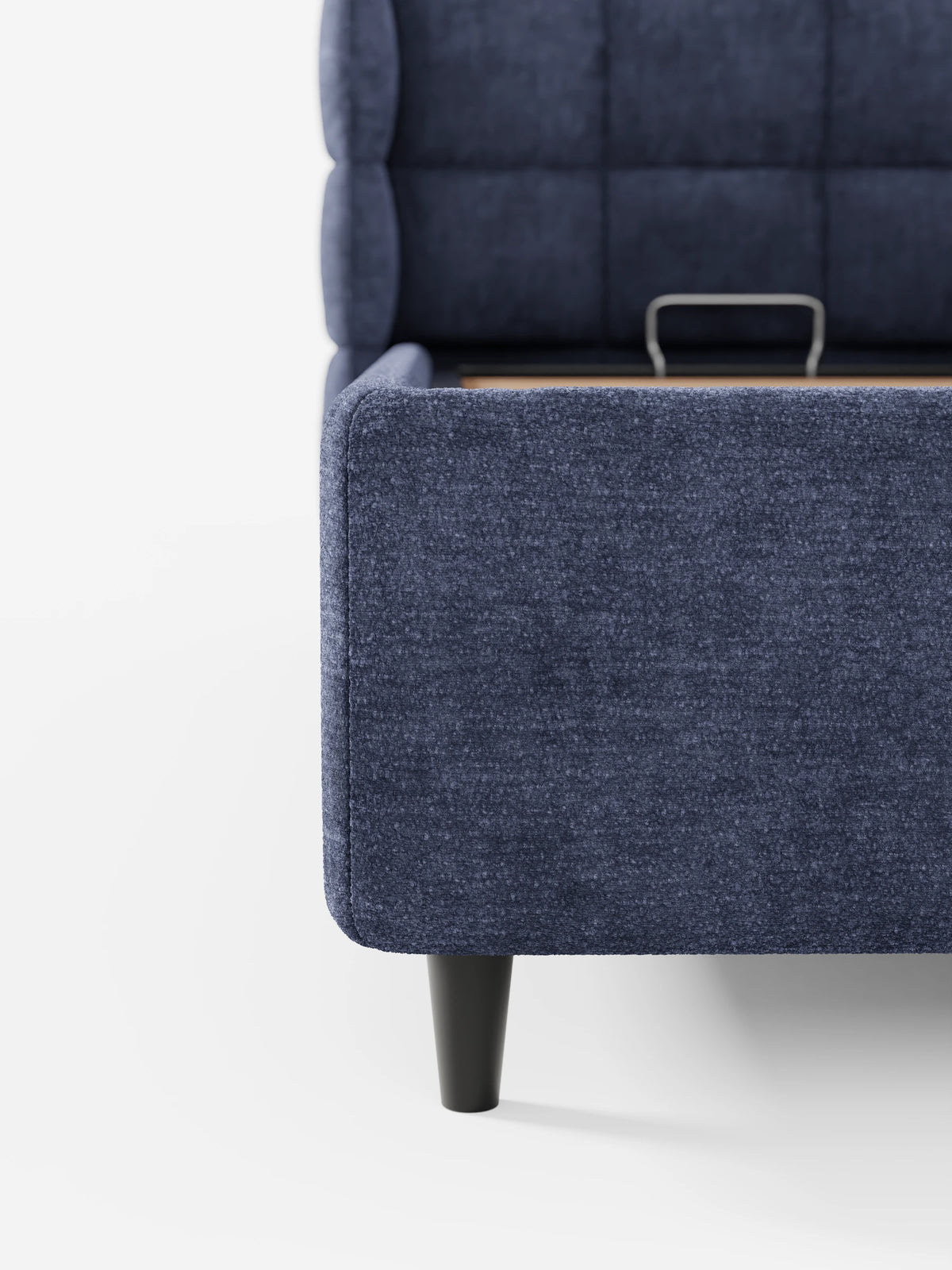 Un primo piano di un letto imbottito RAGNAR blu navy con contenitore e testiera capitonné avvolgente, caratterizzato da un design capitonné con ali laterali ricurve e gambe nere corte e affusolate su uno sfondo bianco a tinta unita.