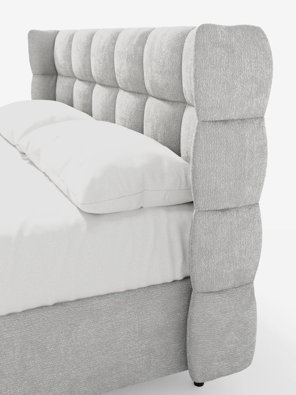 Un primo piano del letto imbottito RAGNAR con contenitore e testiera capitonné avvolgente - elegante tessuto certificato Oeko-Tex®, caratterizzato da una struttura in tessuto grigio testurizzato, un'alta testiera curva trapuntata e biancheria da letto di un bianco candido.