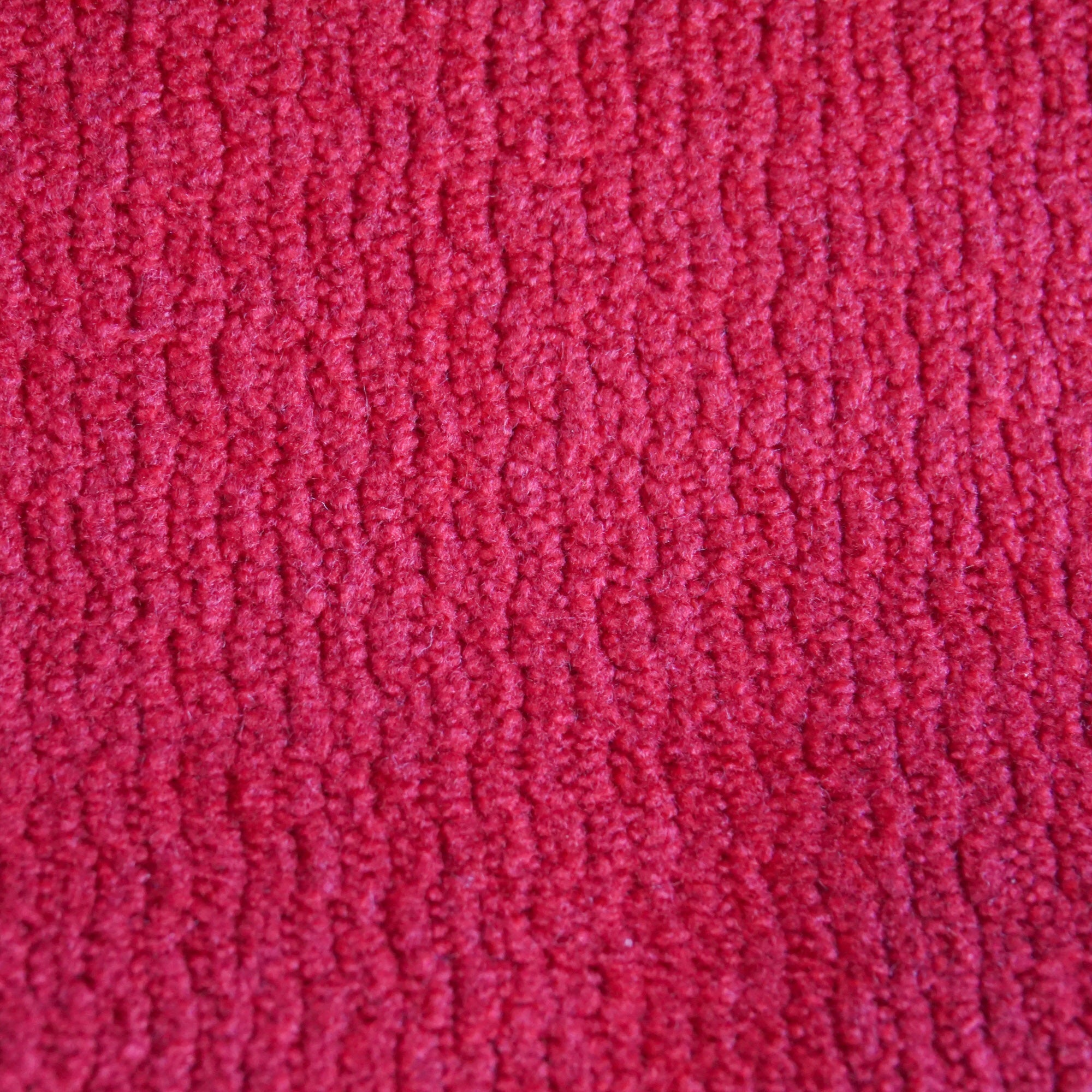 Primo piano di T32 Kendal di Divani.Store: una morbida e soffice microfibra rossa con un motivo verticale a tessuto a coste. Il tessuto, impermeabile e antimacchia, è caratterizzato da fibre fitte per un aspetto accogliente e caldo. Non sono visibili altri oggetti.