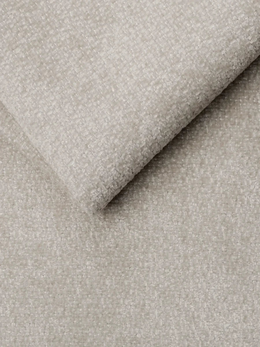 Un primo piano del tessuto materico color beige chiaro del divano letto Ottaviano con letto estraibile – penisola reversibile e contenitore in tessuto materico lavabile, con un angolo ripiegato per mettere in risalto la trama e la consistenza del tessuto.
