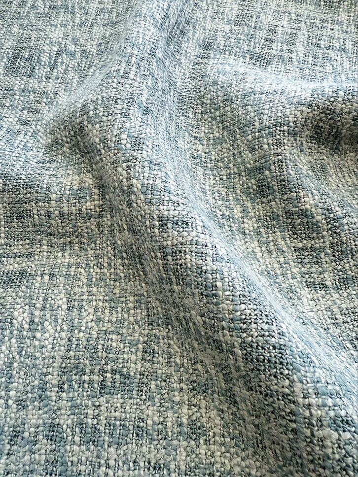Primo piano del tessuto riciclato naturale S07 EARTHWILD, in misto cotone e lino, nei toni dell'azzurro e del bianco, caratterizzato da un motivo rustico e variegato con fili di cotone biologico spessi e tridimensionali.
