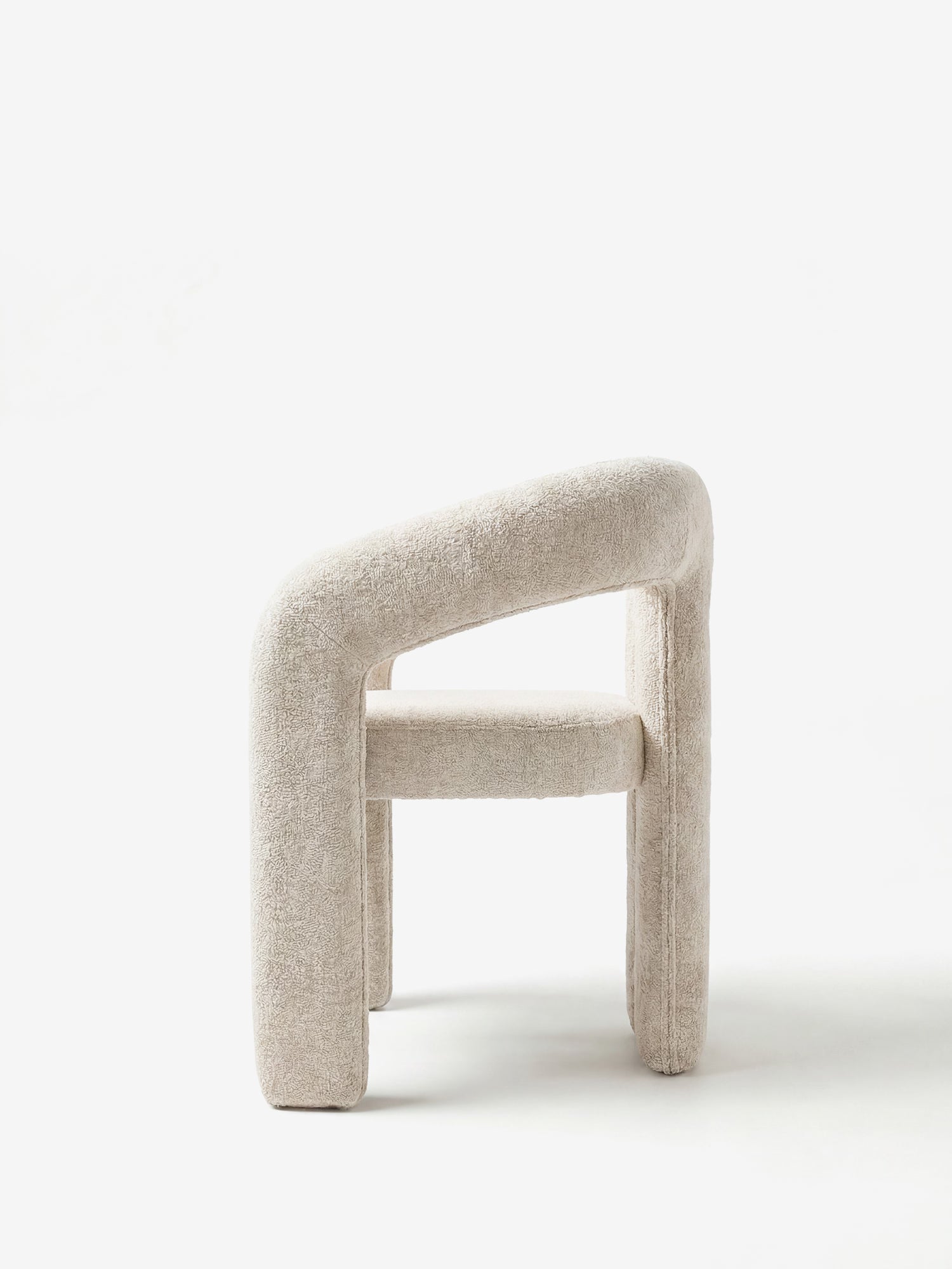 La Sibilla Sedia di design di Divani.Store è una moderna poltrona decorativa con un morbido rivestimento beige chiaro, una forma arcuata e una struttura interamente rivestita in tessuto. Il suo schienale spesso e curvo si fonde armoniosamente con i braccioli e le gambe su uno sfondo bianco a tinta unita.
