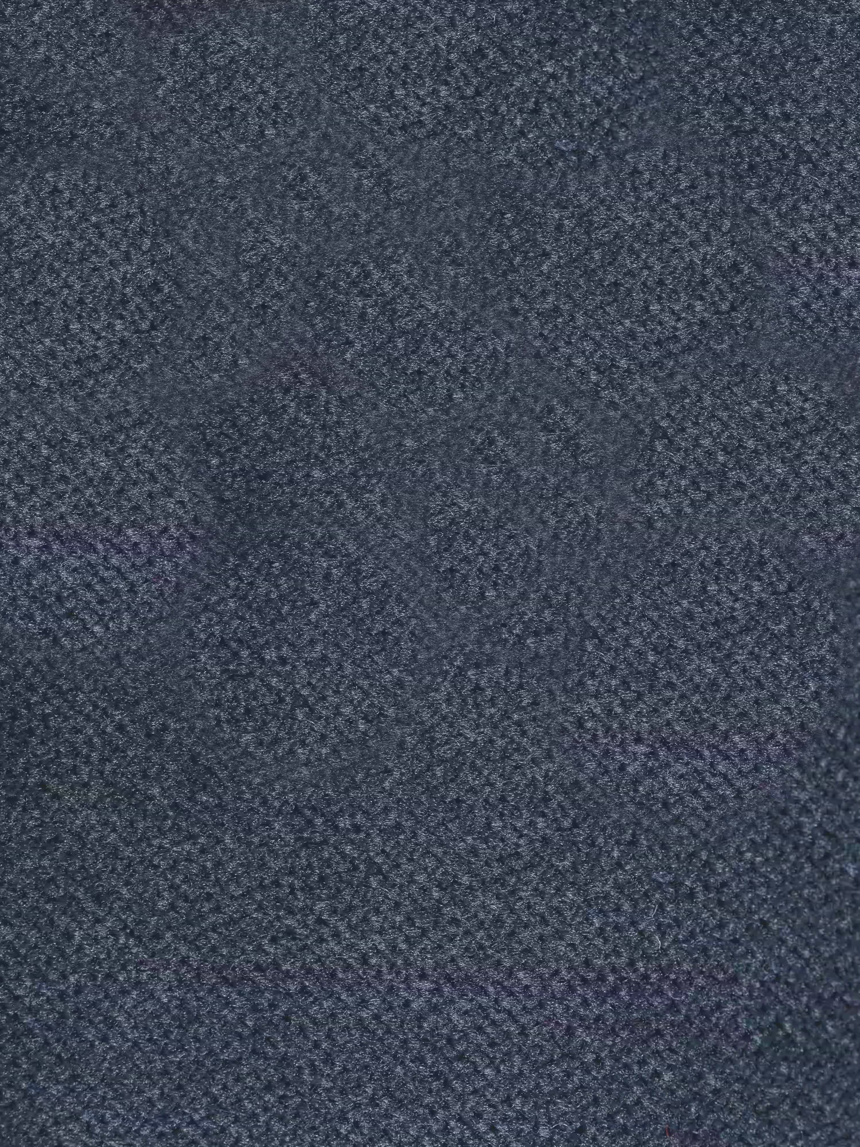 Primo piano del divano letto di design Capri di Divani.Store, realizzato con un raffinato tessuto smacchiabile T30 effetto velluto in blu scuro, caratterizzato da una delicata trama a griglia; il tessuto appare morbido e leggermente screziato, con sfumature di blu che variano su tutta la superficie.