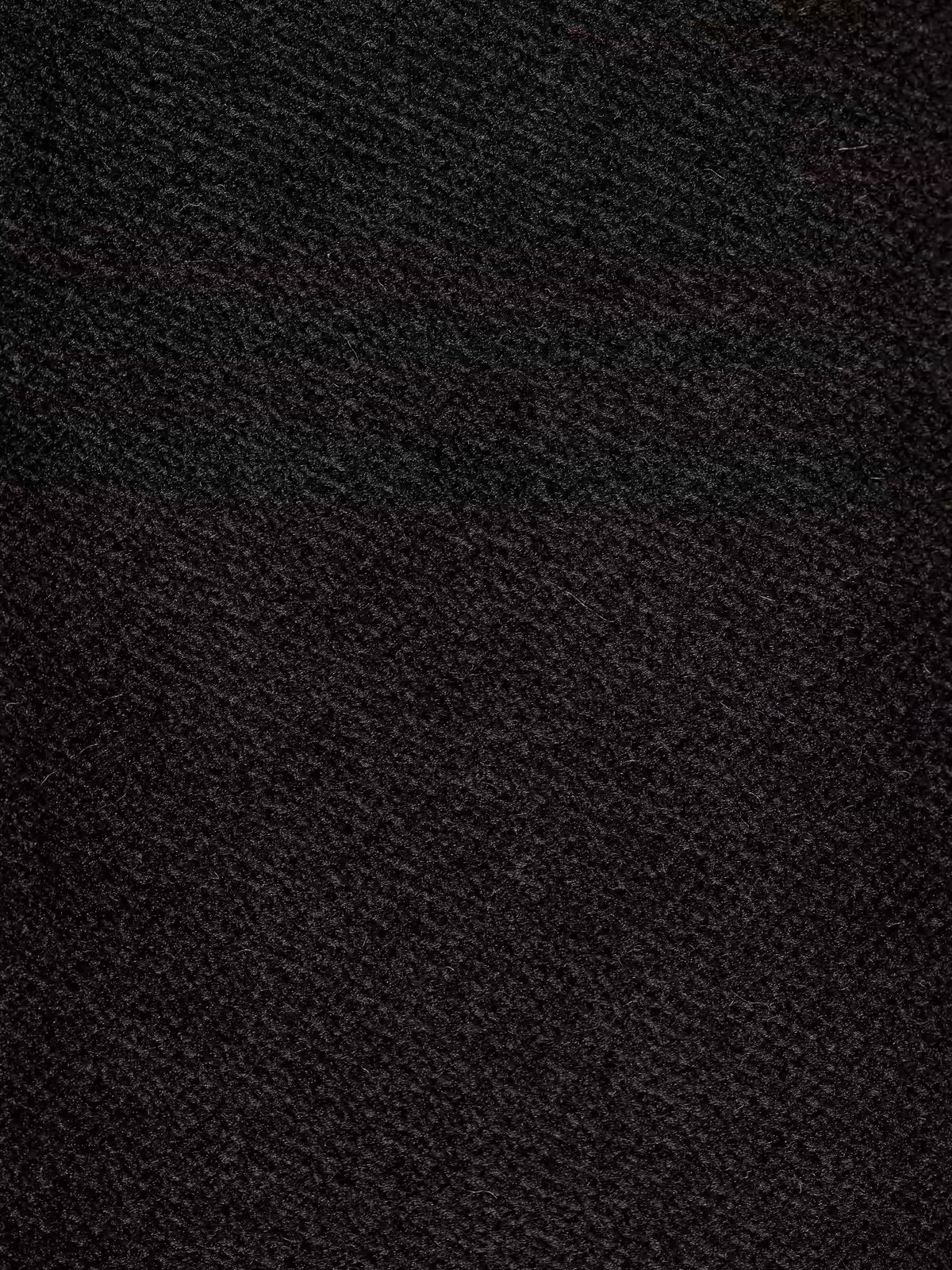 Immagine ravvicinata di una superficie scura con texture, probabilmente il moderno tessuto smacchiabile T30 vellutino del divano letto Dalia a 2, 3 e 4 posti con materasso H18 di Divani.Store. La superficie presenta linee diagonali e sottili variazioni nei toni del nero e del grigio scuro. L'illuminazione accentua il motivo — simile a quello che si troverebbe su un comodo divano letto di alta qualità di Divani.Store — creando un effetto leggermente ruvido e piacevole al tatto. Non sono visibili oggetti
