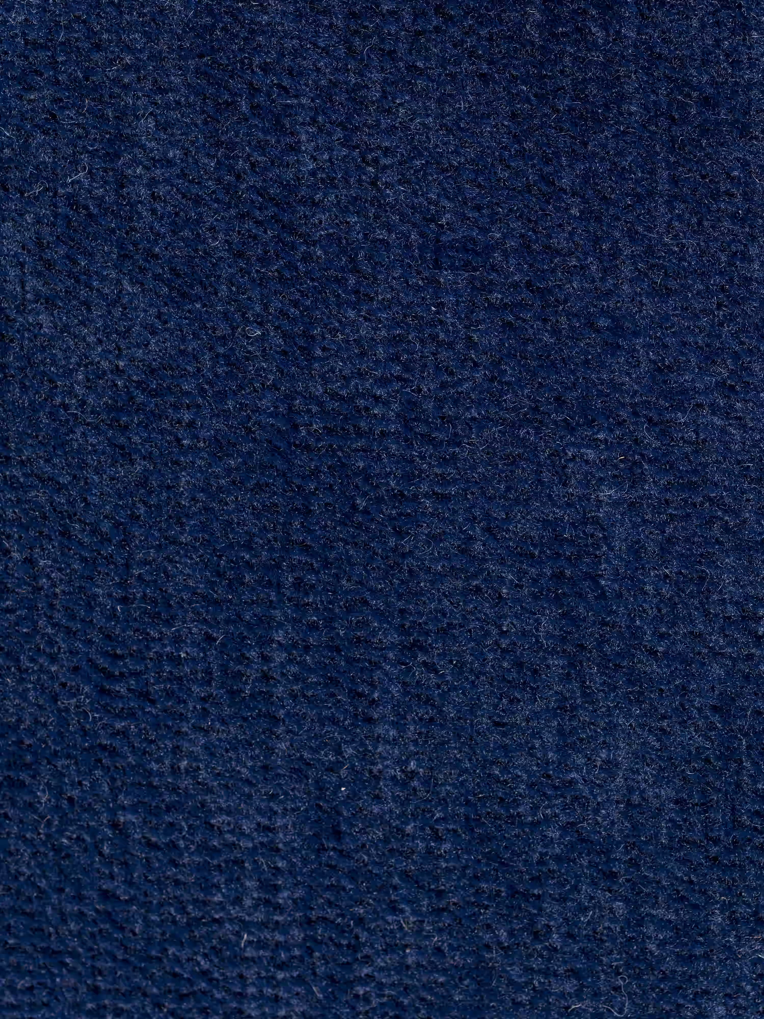 Primo piano di un tessuto blu scuro a trama ruvida della poltrona letto Rift con materasso alto 22 cm e memory foam di Divani.Store, caratterizzato da linee sottili, sottili variazioni di colore e una superficie leggermente sfocata. Il rivestimento dello schienale mobile e lavabile T31 presenta un motivo verticale senza oggetti visibili né segni distintivi.