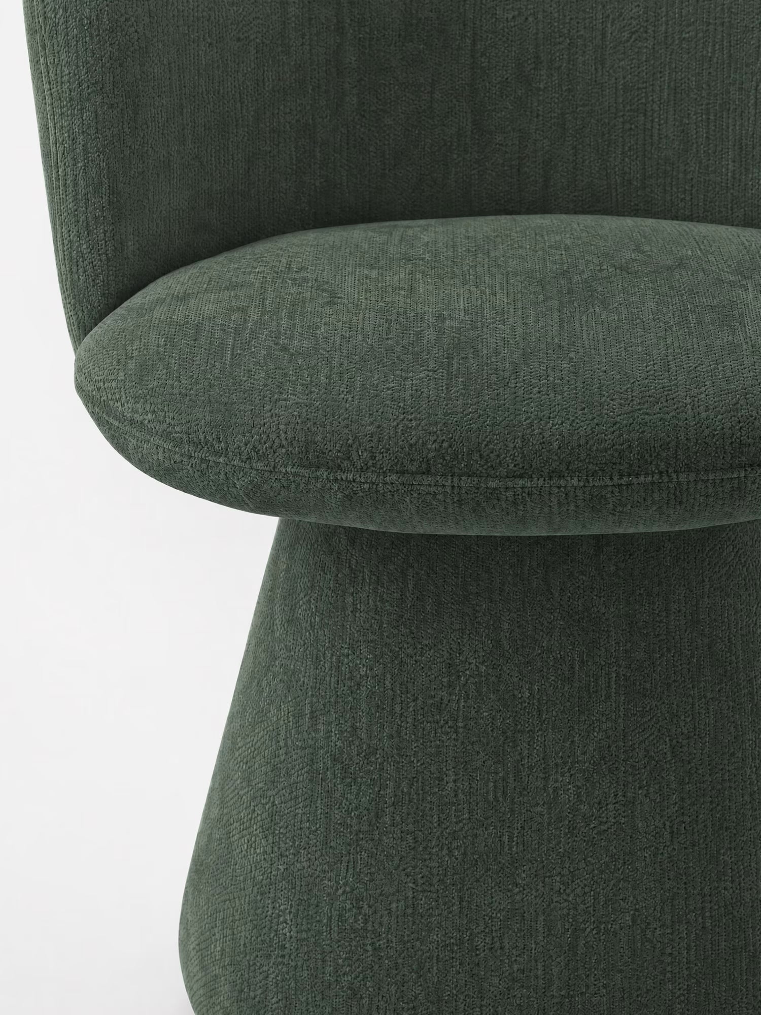 Primo piano della sedia moderna imbottita Talia di Divani.Store, rivestita in tessuto ciniglia verde scuro certificato OEKO-TEX®, che mette in risalto la seduta curva, il design minimalista e le linee morbide su uno sfondo bianco a tinta unita.