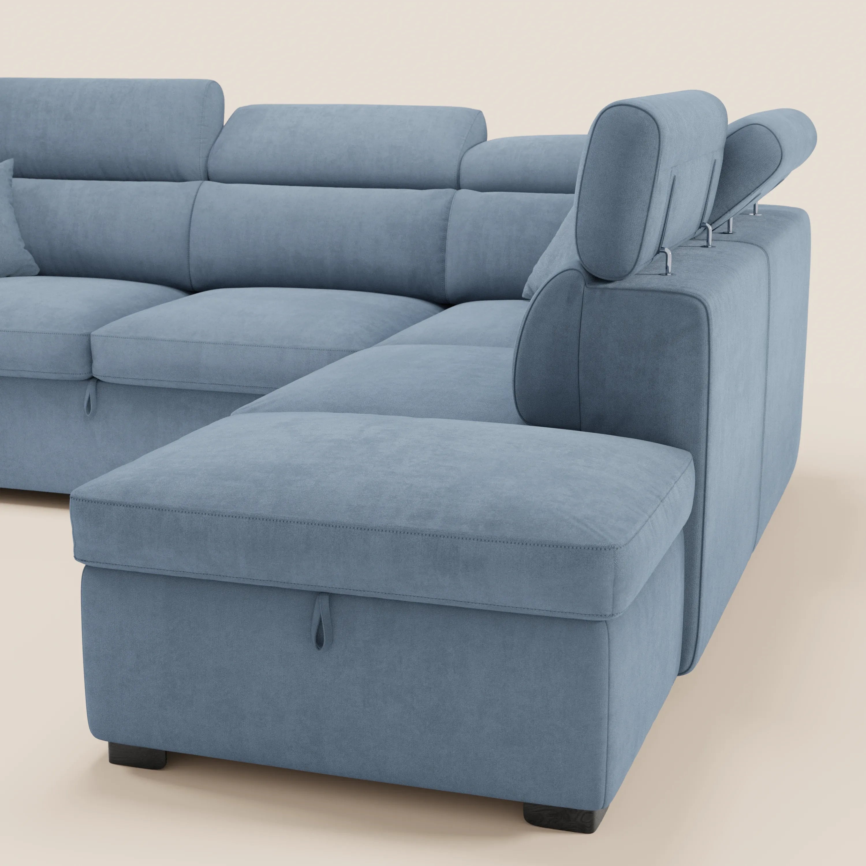 Il divano angolare reversibile Titano di Divani.Store, qui raffigurato in tessuto azzurro certificato Oeko-Tex®, è dotato di poggiatesta regolabili, morbidi cuscini, una chaise longue con letto estraibile e un pouf contenitore su uno sfondo beige chiaro.