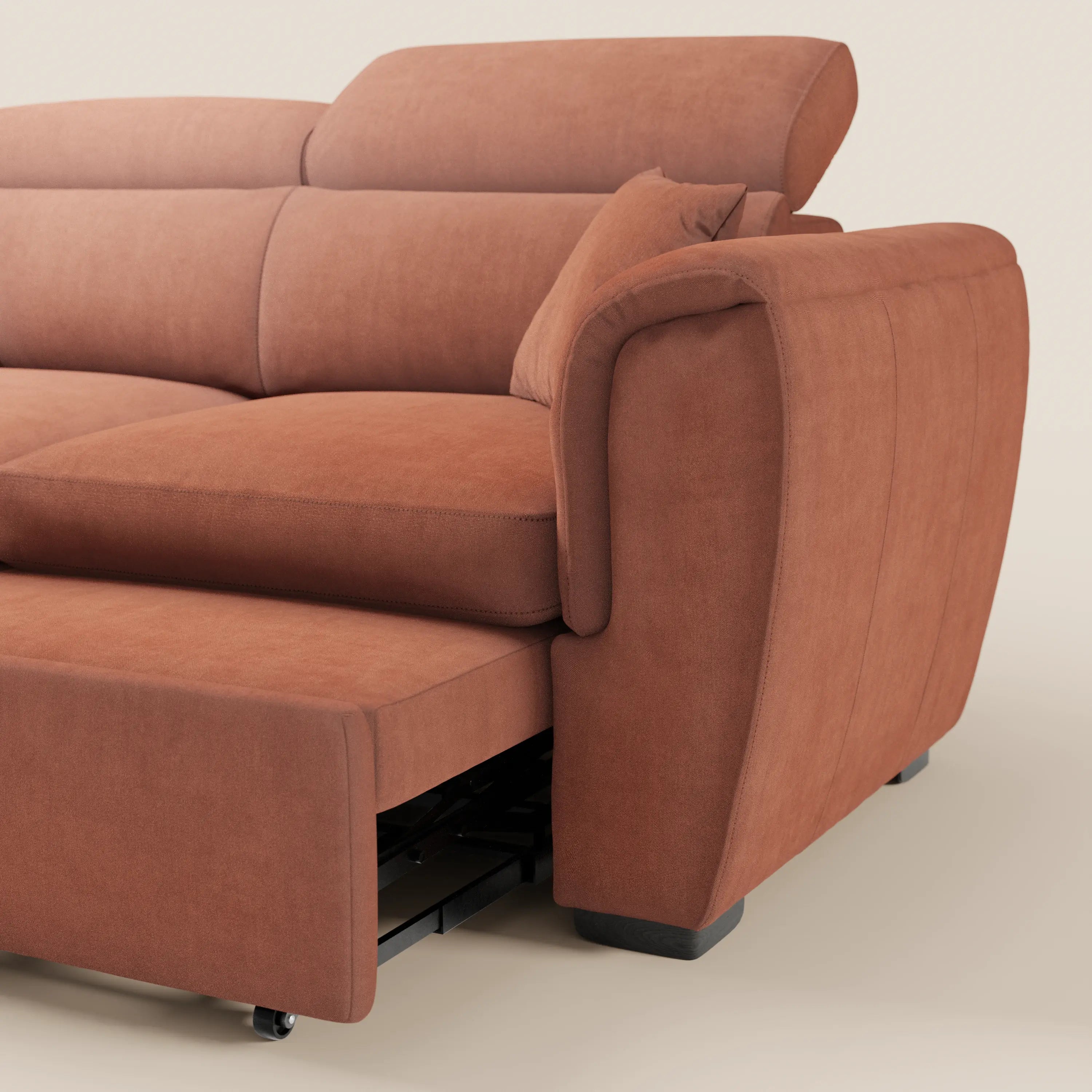 Un primo piano del divano a 2 posti estraibile Titano di Divani.Store, caratterizzato da morbidi cuscini, braccioli arrotondati, poggiatesta regolabili e un letto estraibile. Rivestito in tessuto antimacchia certificato Oeko-Tex®. Lo sfondo è a tinta unita e di colore chiaro.