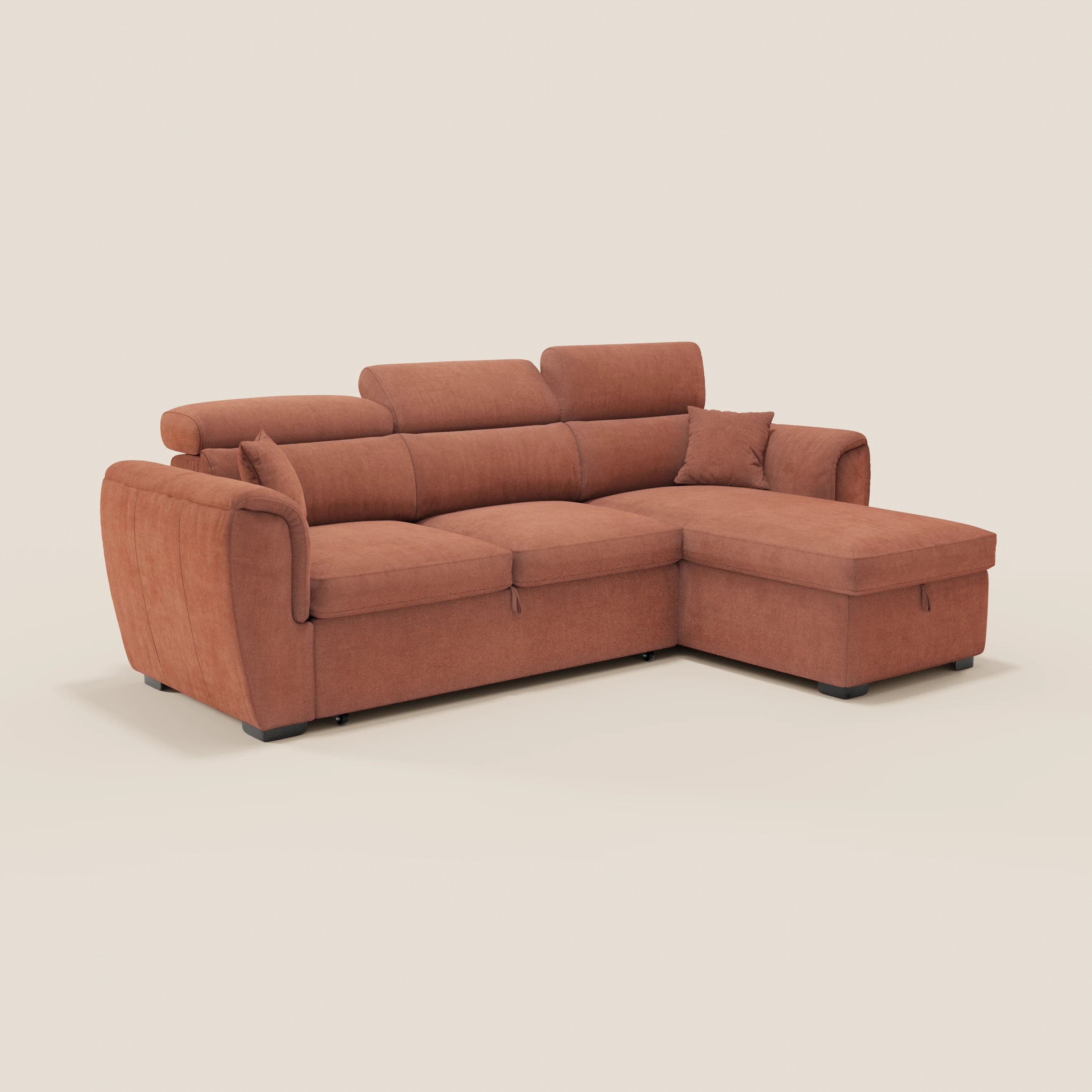 Il divano letto Titano di Divani.Store è caratterizzato da un tessuto color ruggine resistente alle macchie, morbidi cuscini, poggiatesta reclinabili, una chaise longue reversibile con vano portaoggetti e letto estraibile, gambe basse nere e un cuscino coordinato su uno sfondo chiaro.