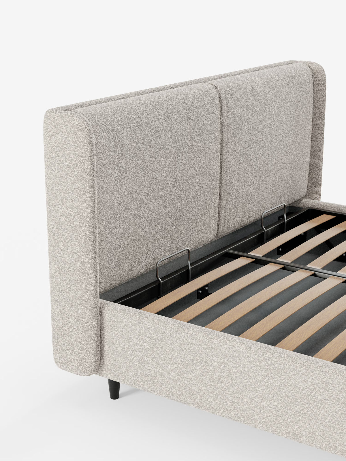 Un letto di design contemporaneo VALKIRIA di Letti.store, caratterizzato da una testiera avvolgente in tessuto beige chiaro certificato Oeko-Tex® con due cuscini imbottiti, gambe nere e doghe in legno a vista. L'immagine in primo piano mostra l'angolo e una parte della testiera, mettendo in risalto i dettagli minimalisti che incarnano un design contemporaneo.