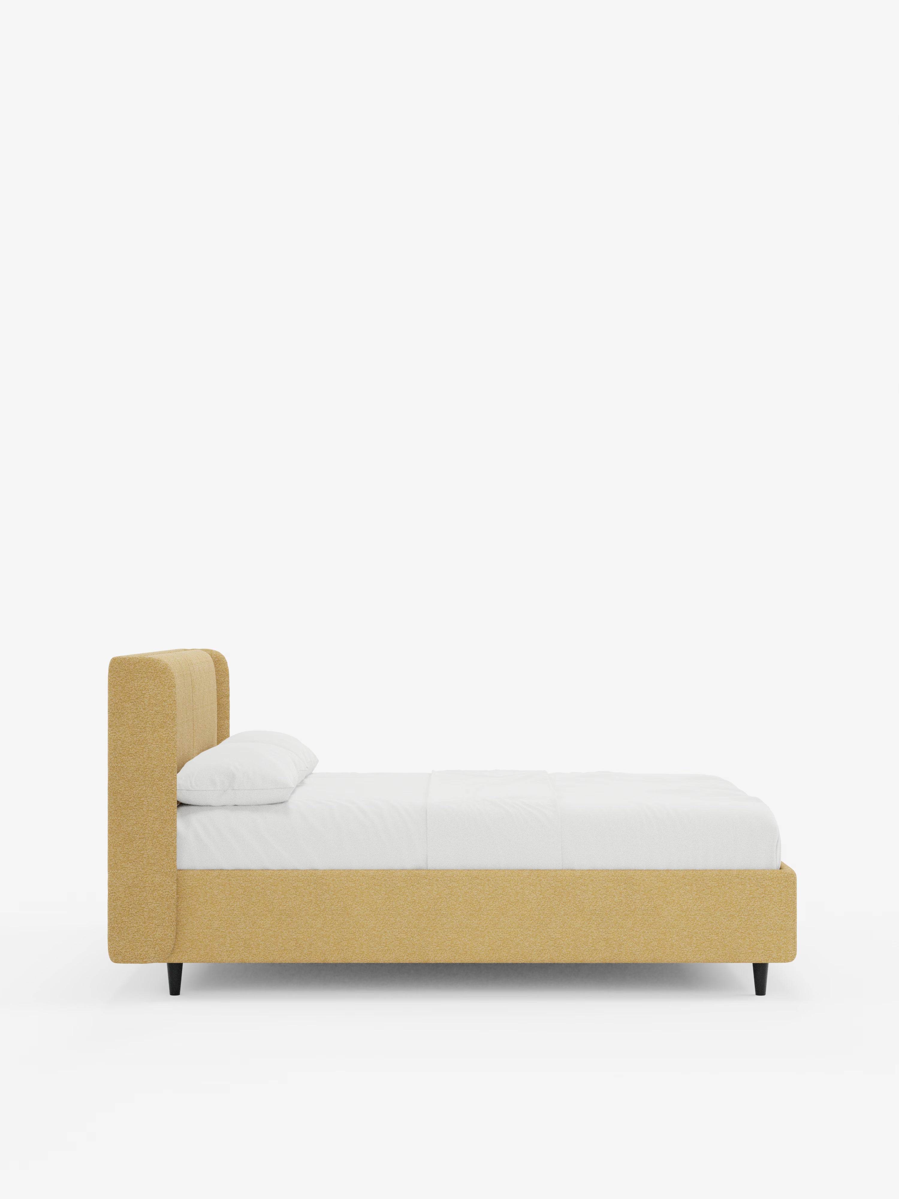 Una vista laterale del letto di design VALKIRIA con vano contenitore e testiera avvolgente di Letti.store, caratterizzato da una struttura e una testiera rivestite in tessuto giallo senape certificato Oeko-Tex® con due cuscini imbottiti, gambe angolate nere, biancheria da letto candida e un cuscino bianco, il tutto su uno sfondo bianco a tinta unita. Questo elegante letto imbottito incarna il design contemporaneo, unendo stile e comfort in ogni ambiente notte.