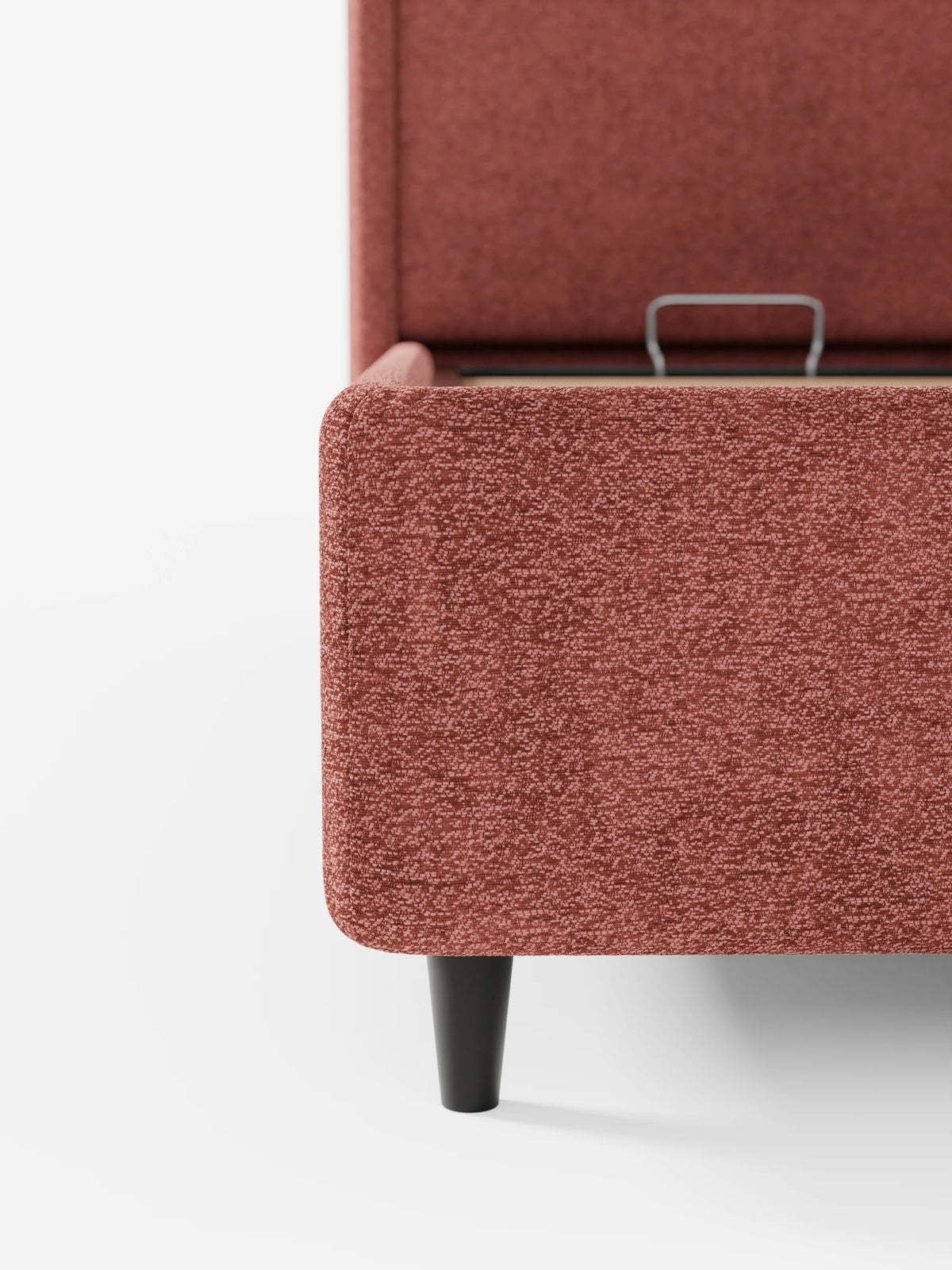 Dettaglio angolare del letto di design VALKIRIA con vano contenitore e testiera avvolgente in tessuto effetto terracotta, che mostra la testiera alta, le gambe corte e affusolate di colore nero e il vano contenitore rialzato con il relativo meccanismo interno in metallo.