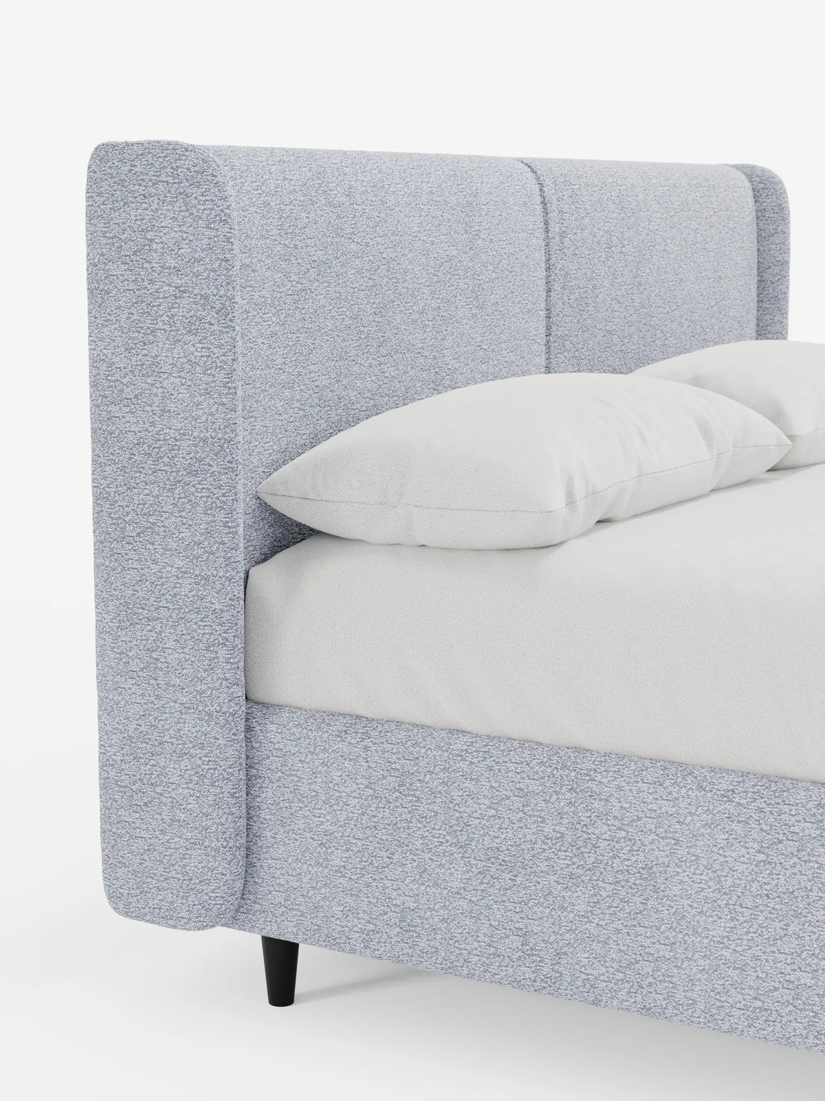 Il letto di design VALKIRIA con contenitore e testiera avvolgente è un letto moderno e imbottito, caratterizzato da un'alta testiera avvolgente di colore azzurro con finitura testurizzata, due morbidi cuscini bianchi e gambe corte e scure di forma cilindrica che risaltano sullo sfondo bianco.