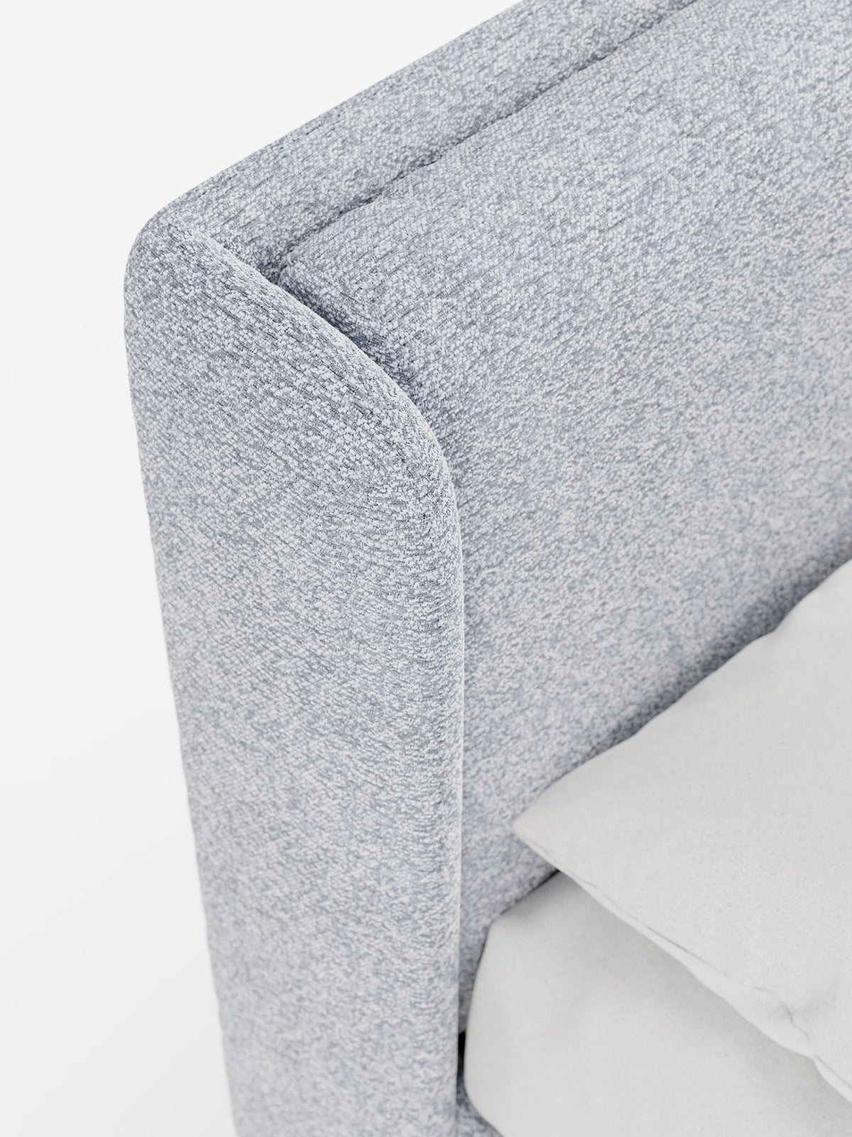 Un primo piano del letto di design VALKIRIA con contenitore e testiera avvolgente, caratterizzato da una testiera imbottita di colore azzurro con un design curvo e avvolgente, tessuto a trama fine e un morbido cuscino di colore chiaro.