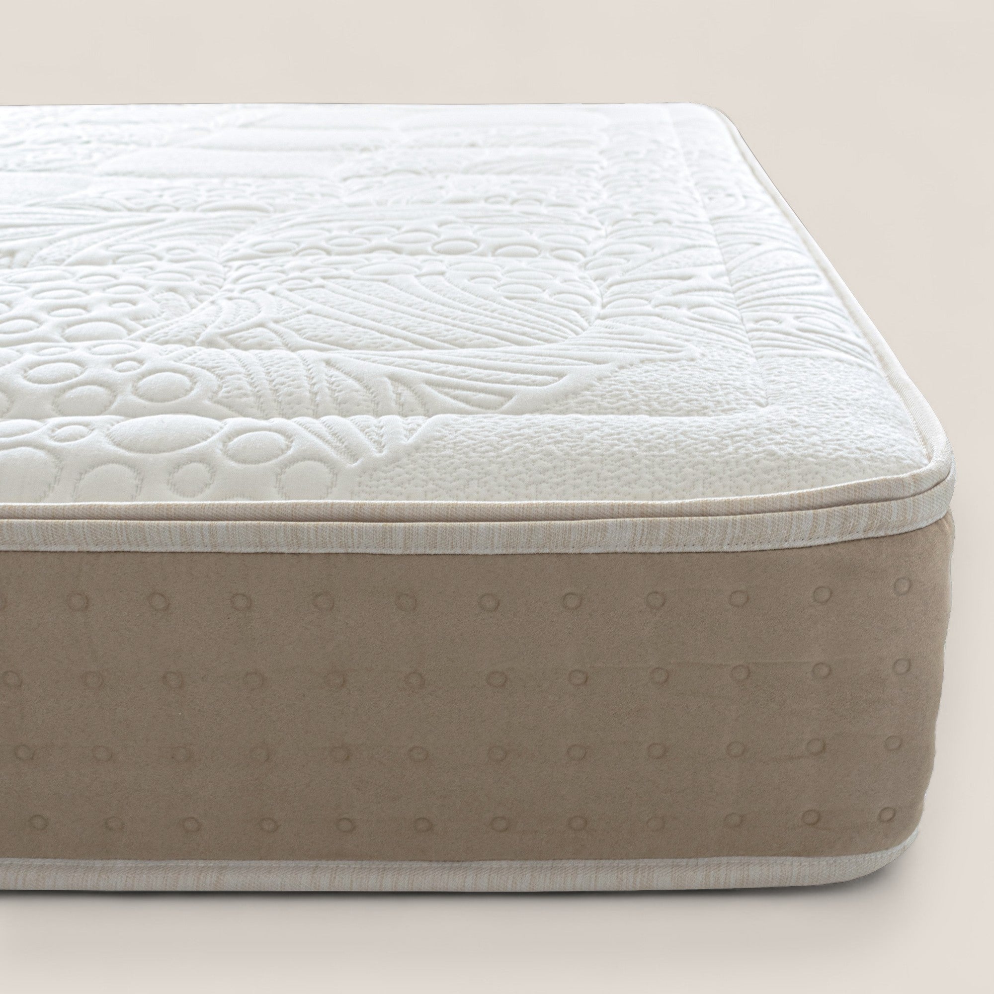 Primo piano del materasso VELTHA Bio-Adaptive di Divani.Store, caratterizzato da un piano bianco strutturato con intricati motivi naturali a reticolo e un pannello laterale beige con cerchi uniformemente distanziati, su uno sfondo neutro chiaro.