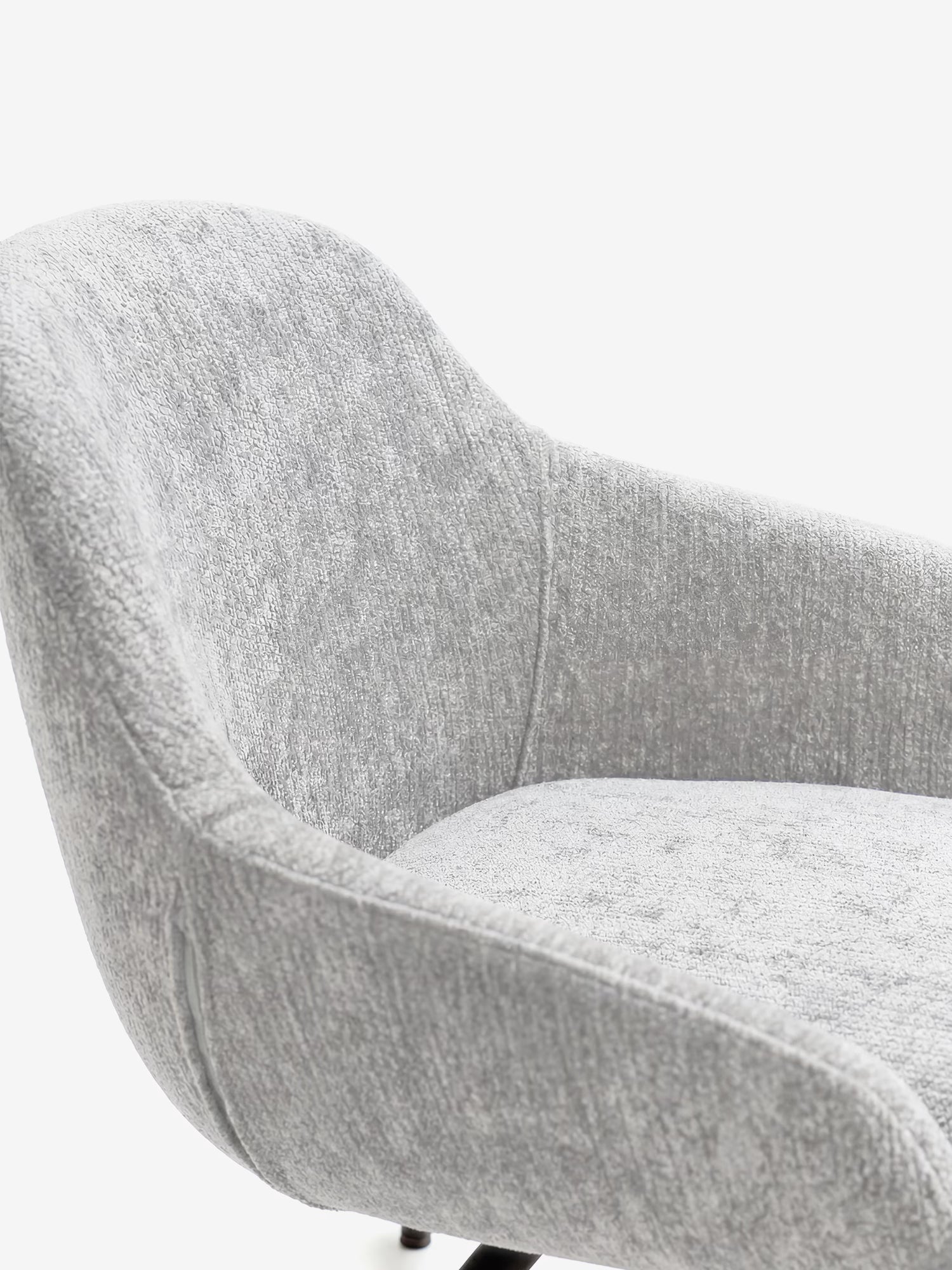 Primo piano della sedia imbottita Vico di Divani.Store, realizzata in tessuto soft-touch grigio chiaro certificato OEKO-TEX®, con schienale curvo e gambe in metallo nero. Il design arrotondato risalta sullo sfondo bianco, mettendo in evidenza parte della seduta e della struttura.