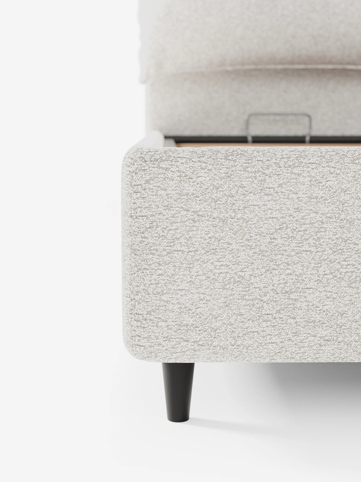 Il letto imbottito ZAYRON con vano contenitore e morbidi cuscini regolabili presenta una finitura imbottita color beige chiaro, un tessuto dalla trama morbida e gambe affusolate scure, con la struttura aperta che lascia intravedere un vano contenitore interno.