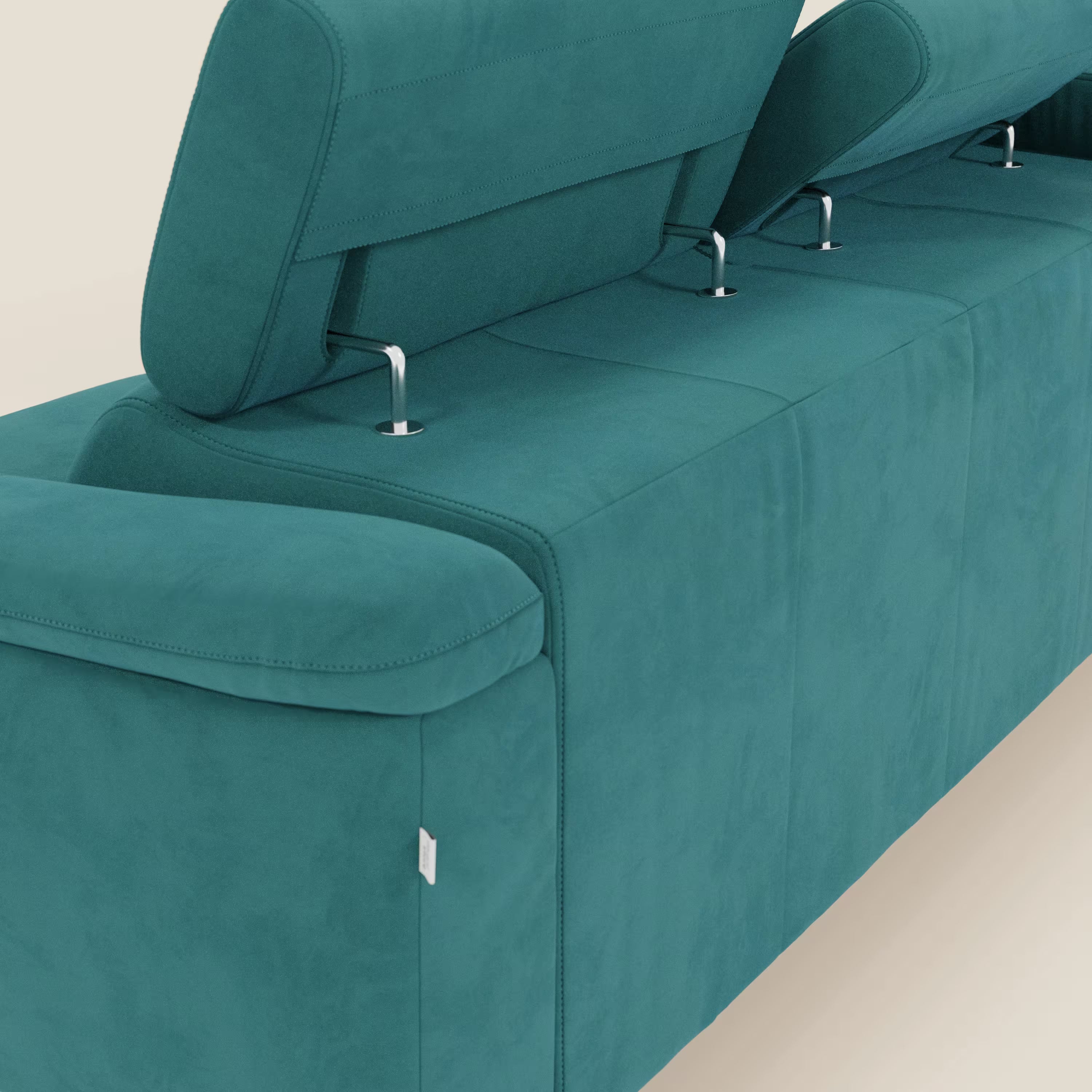 Un primo piano di Arcos Divano con penisola di Divani.Store in T11 petrolio mostra due poggiatesta regolabili su supporti metallici, braccioli morbidi, cuciture a vista e targhetta bianca, il tutto in microfibra impermeabile ad alta manifattura italiana.