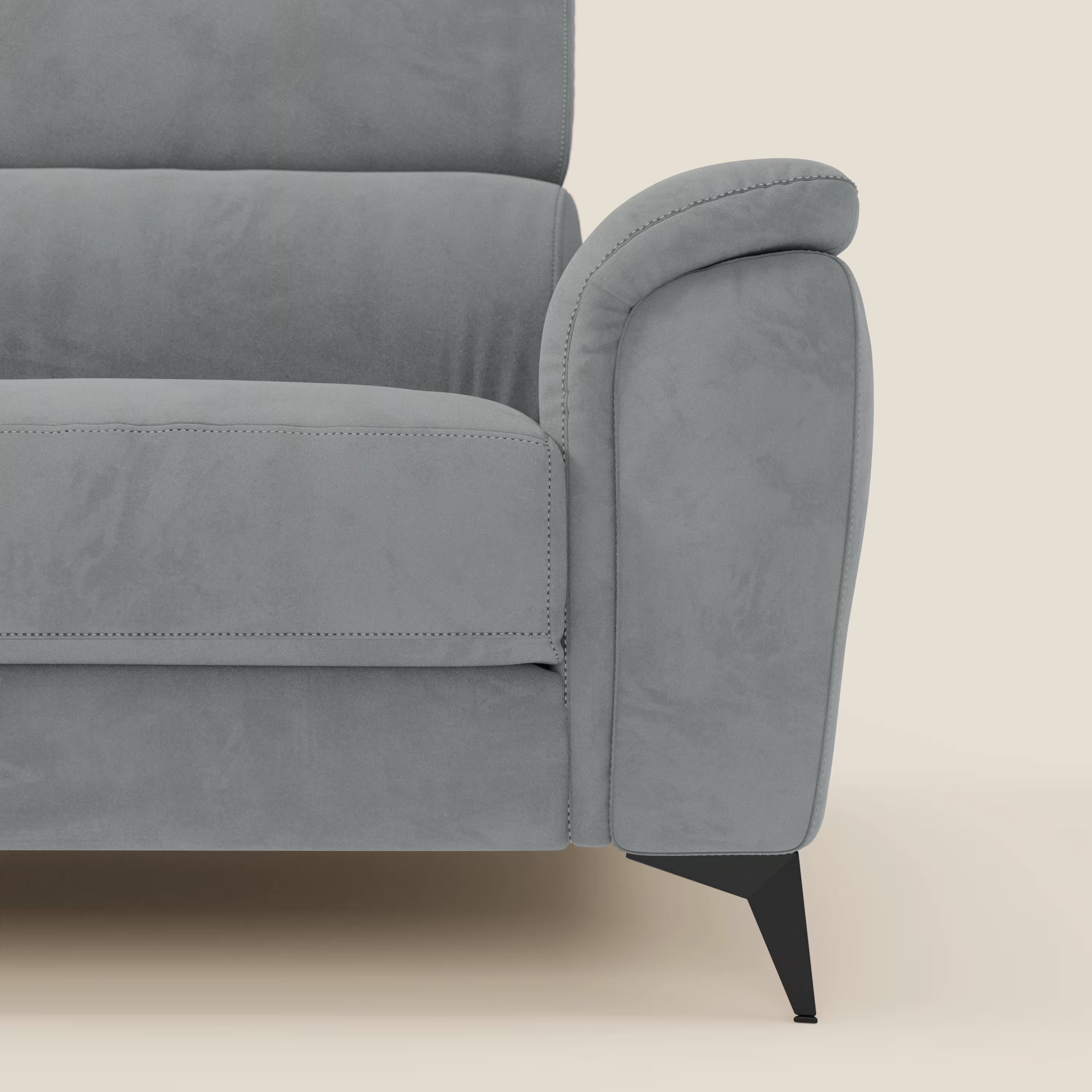 Primo piano del bracciolo destro e della seduta di Arcos Divano 3 posti di Divani.Store, con braccioli morbidi e arrotondati e sottili gambe in metallo nero in microfibra impermeabile grigio T11, su sfondo beige chiaro.