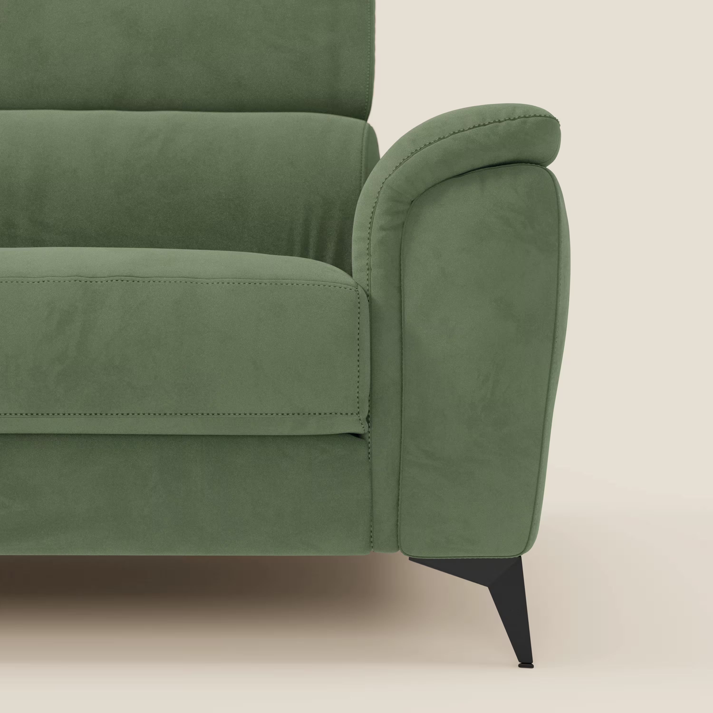 Primo piano del braccio destro e della seduta di Arcos Divano 3 posti di Divani.Store, caratterizzato da una morbida imbottitura, un bracciolo arrotondato e sottili gambe angolari nere in microfibra impermeabile verde T11, su uno sfondo beige chiaro.