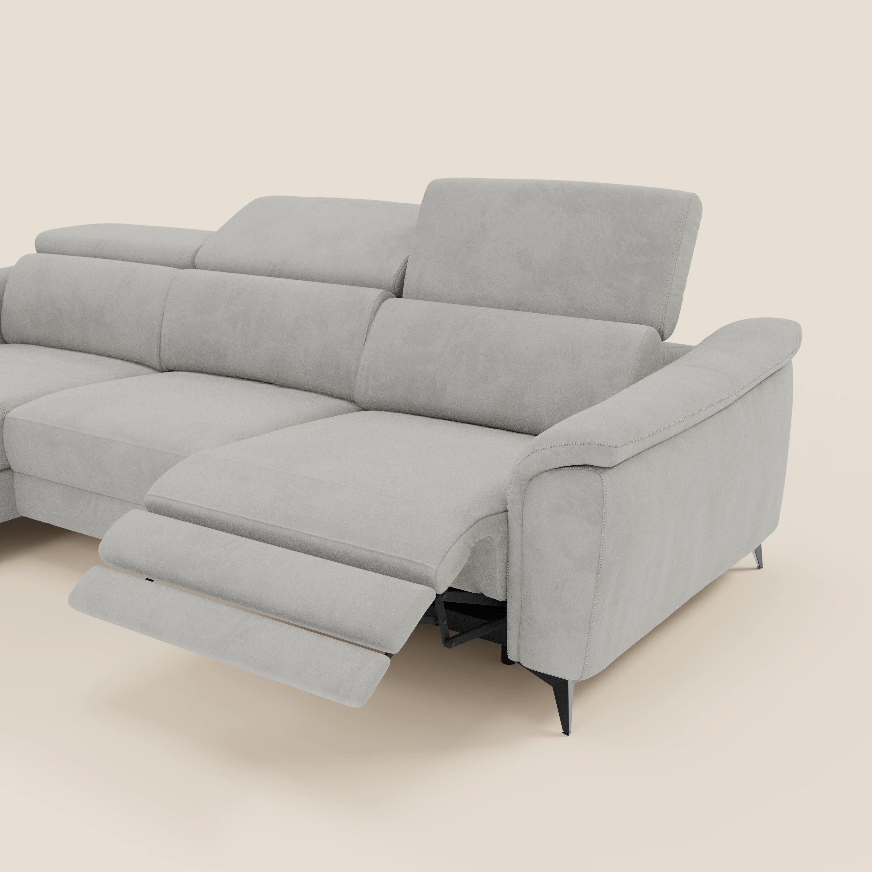 L'Arcos Divano con penisola di Divani.Store in microfibra impermeabile grigio chiaro T11 è caratterizzato da gambe alte, poggiatesta reclinabili e chaise longue su sfondo beige.