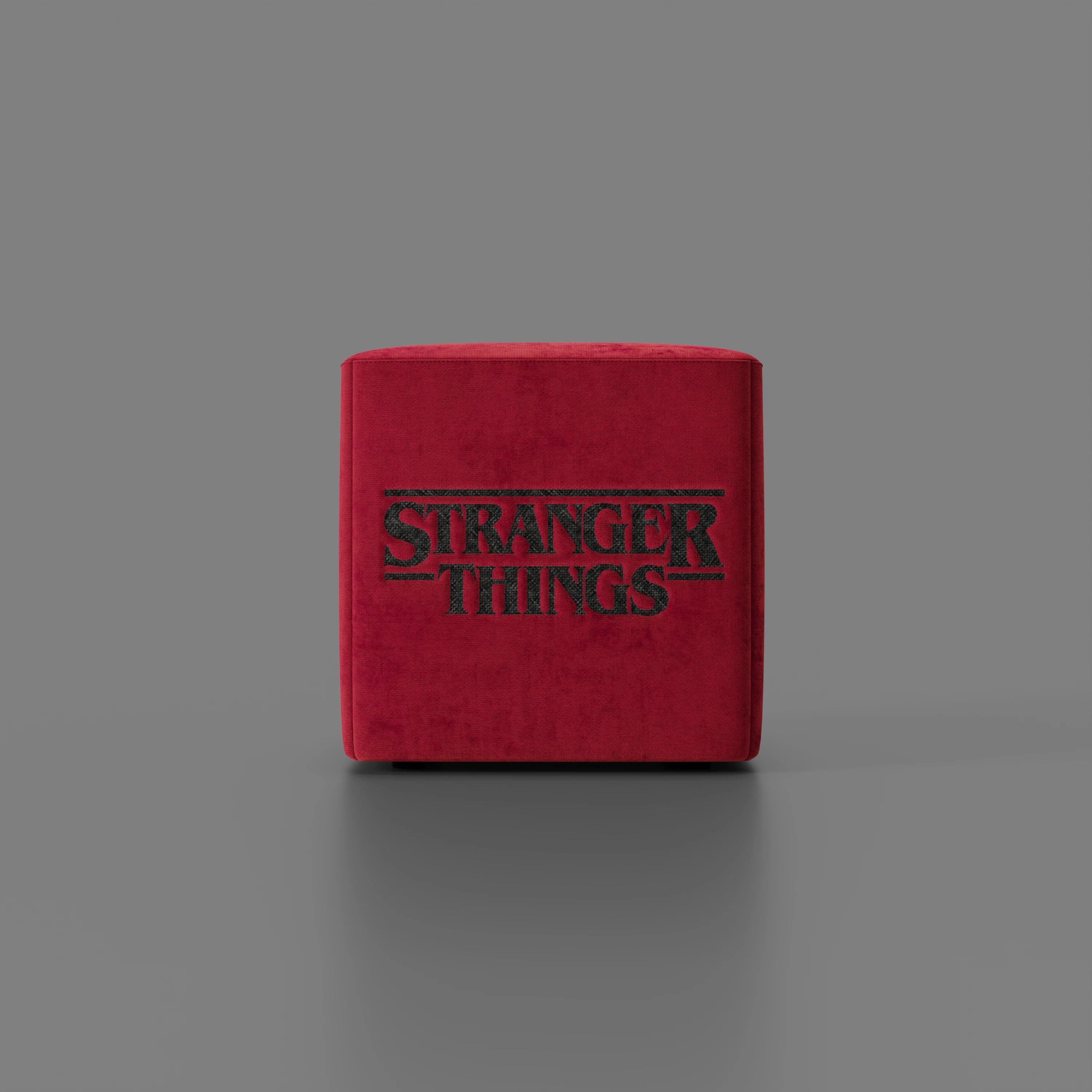 Il pouf Cube Stranger Things Edition di Divani.Store si trova su uno sfondo grigio, con l'iconico logo in nero. Realizzato in tessuto antimacchia, questo accogliente complemento d'arredo è perfetto per il salotto di ogni fan.