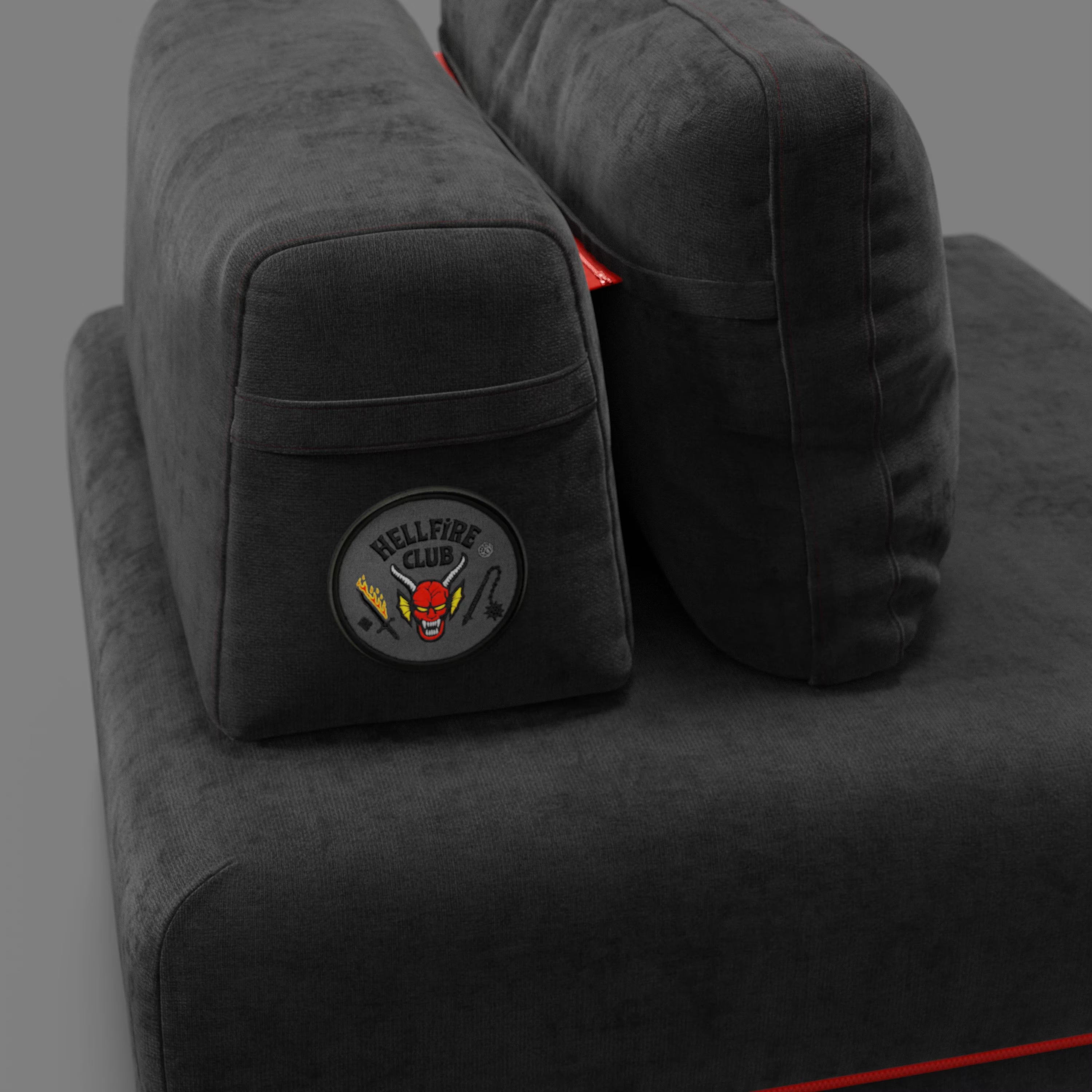 Primo piano della poltrona letto Rift STRANGER THINGS Edition di Divani.Store, in tessuto antracite antimacchia con materasso in memory foam da 22 cm e patch "HELLFIRE CLUB". Lo sfondo è semplice e grigio.