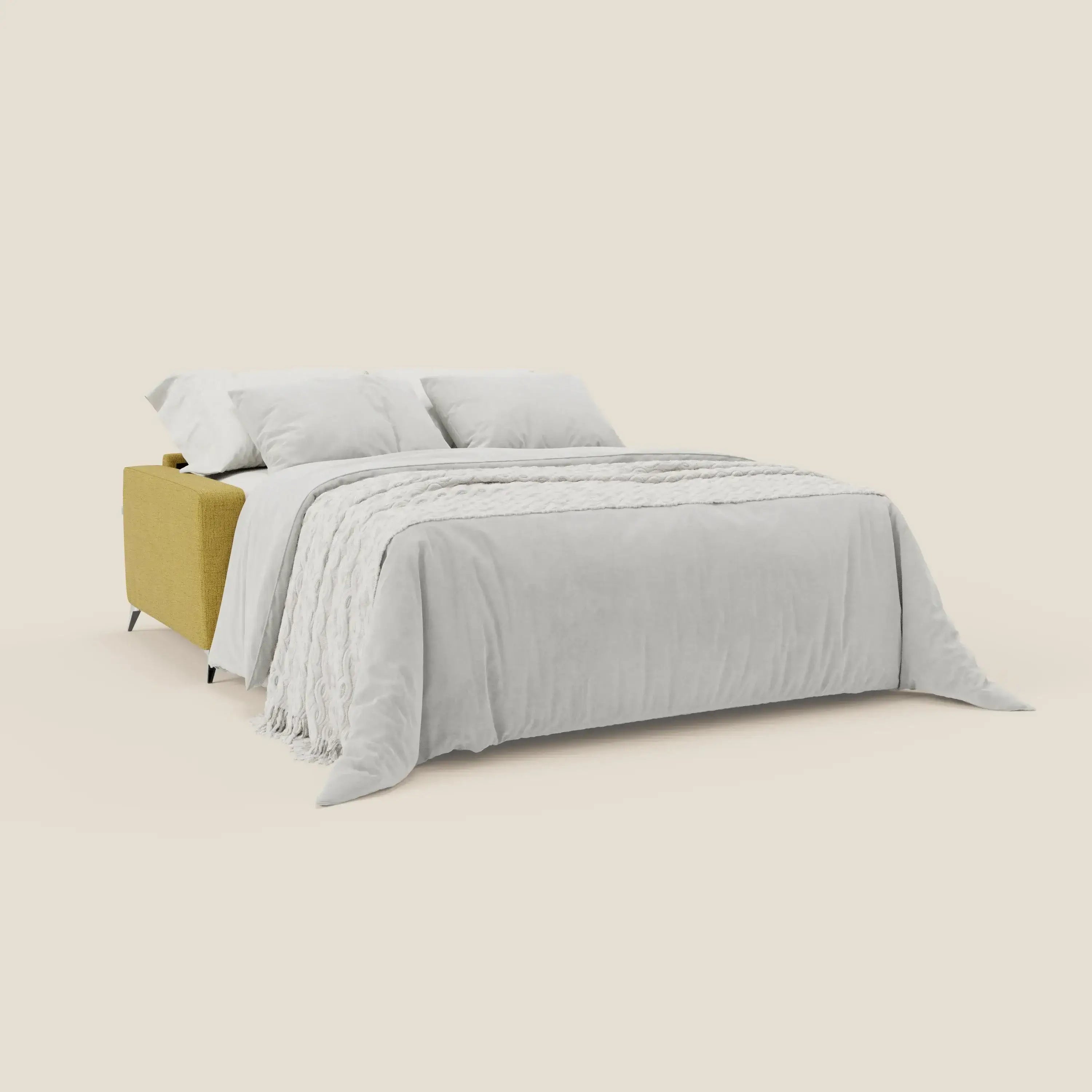 Il divano letto matrimoniale Alaya di Divani.Store in tessuto impermeabile T03 giallo è presentato come letto allungato con un piumone grigio chiaro, una coperta bianca con frange e due grandi cuscini bianchi per un look calmo e minimale.