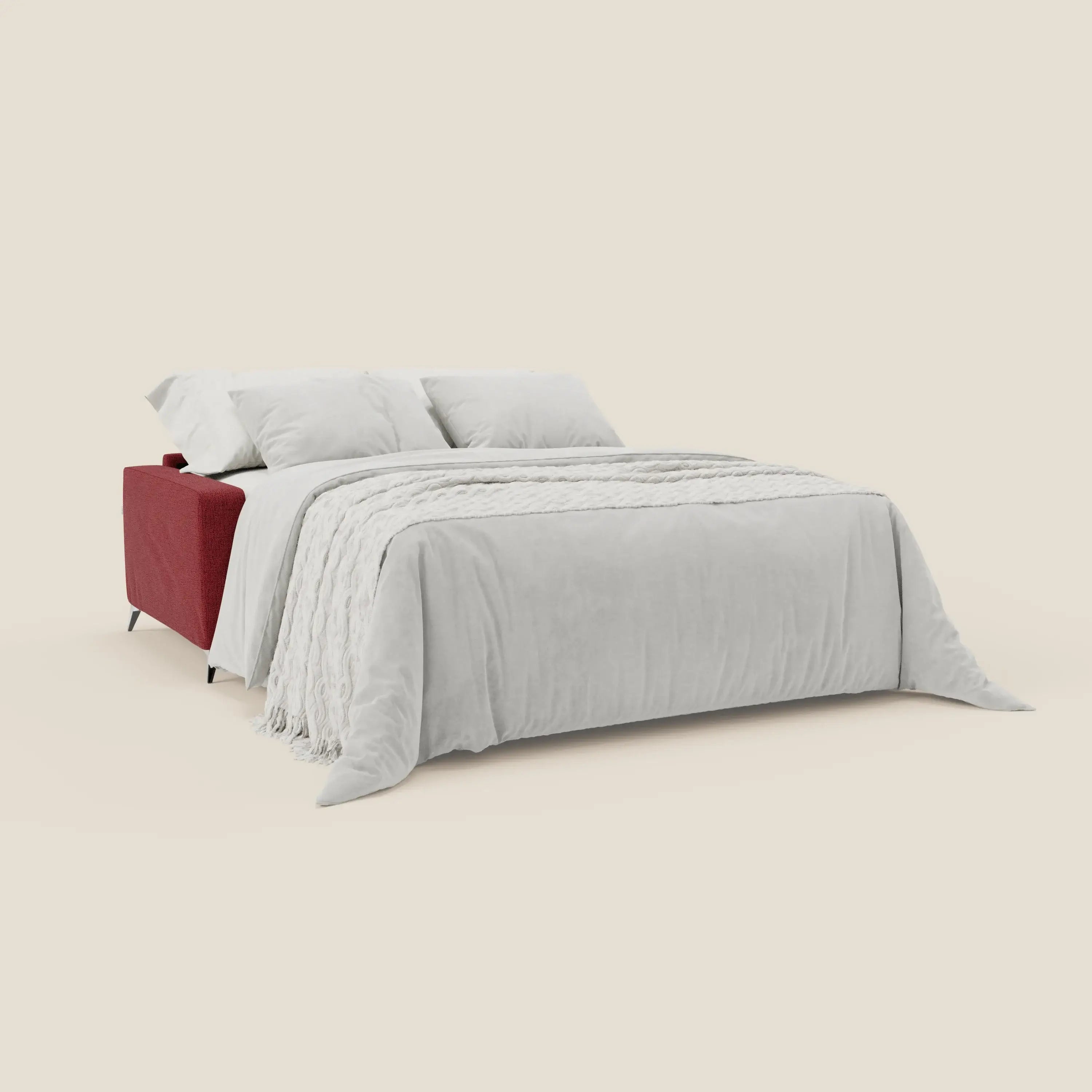 Il letto matrimoniale Alaya Divano di Divani.Store è caratterizzato da morbidi cuscini in tessuto impermeabile rosso T03, un design moderno e minimalista con quattro gambe sottili, biancheria da letto bianca, due cuscini e una coperta bianca testurizzata su uno sfondo beige chiaro.