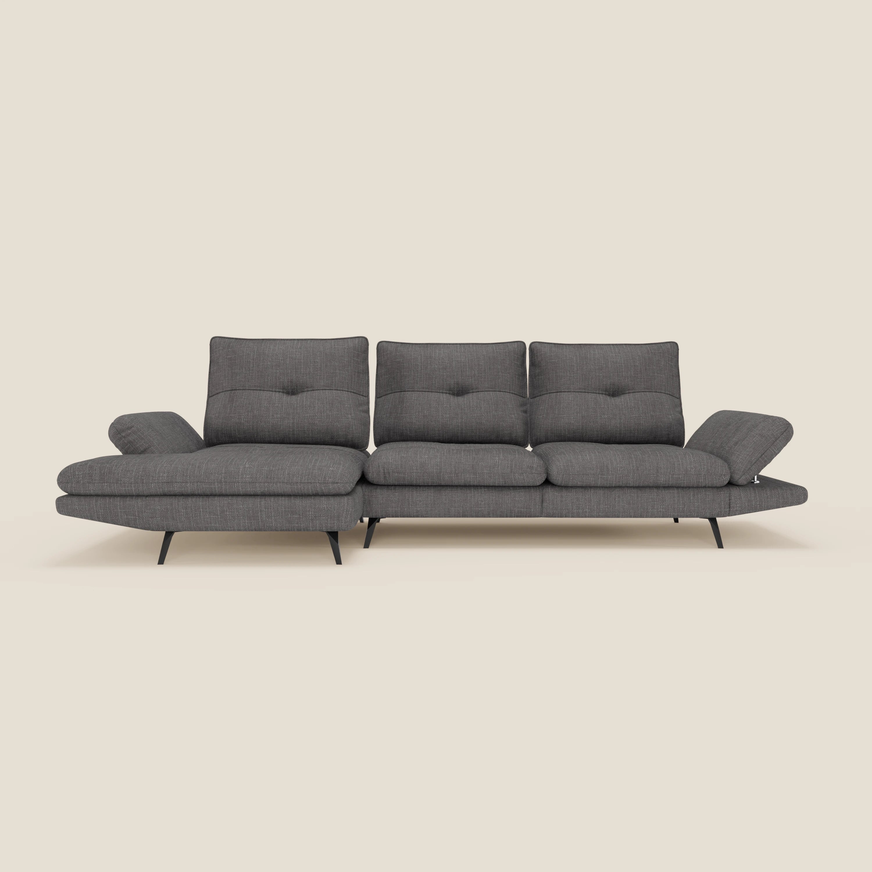 Il Divano con penisola Ardex di Divani.Store è caratterizzato da schienali traslanti, braccioli regolabili ed elegante tessuto impermeabile T06 antracite. Ha tre cuscini di schienale trapuntati, una sezione chaise a sinistra e gambe angolate nere. Lo sfondo è beige chiaro.