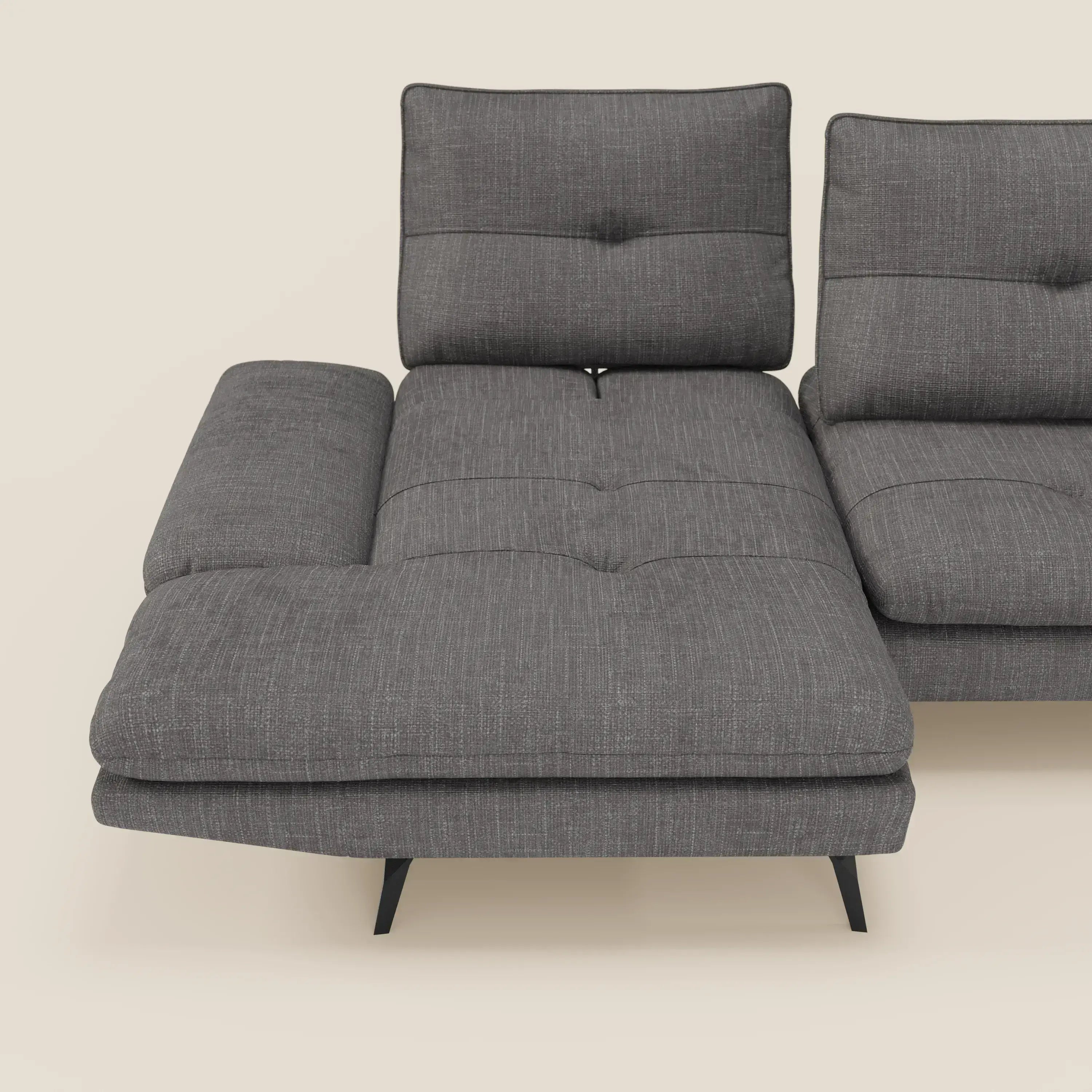 L'Ardex Divano con penisola di Divani.Store presenta schienali traslanti, braccioli regolabili e l'elegante tessuto impermeabile T06 antracite, con la sezione chaise che si estende in avanti su sottili gambe nere su uno sfondo beige.