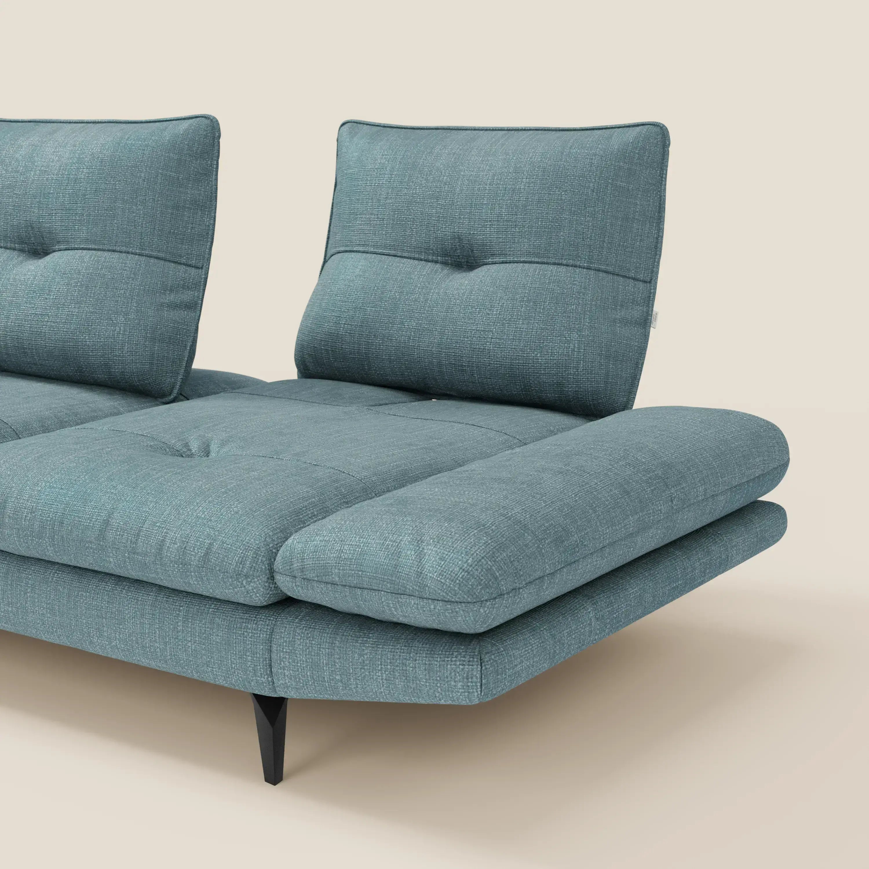 Il Divano con penisola Ardex di Divani.Store, presentato in tessuto impermeabile T06 azzurro con schienali traslanti e braccioli regolabili, poggia su sottili gambe nere in un ambiente minimalista con sfondo beige chiaro. Il lato destro e il frontale sono visibili.