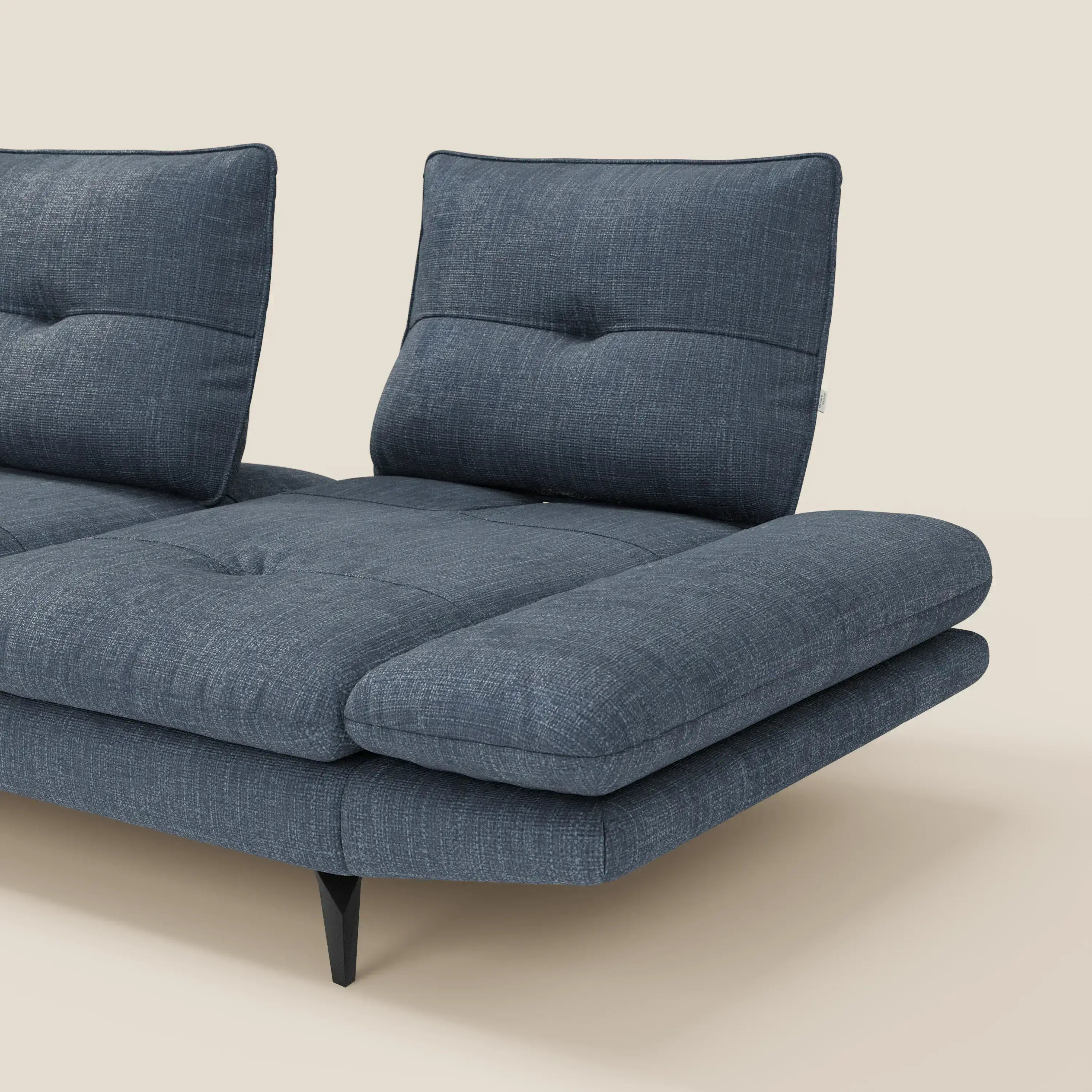 Il Divano con penisola Ardex di Divani.Store è caratterizzato da schienali traslanti, braccioli regolabili ed elegante tessuto impermeabile T06 blu. Il divano angolare moderno con due schienali è mostrato solo in parte, su uno sfondo beige.