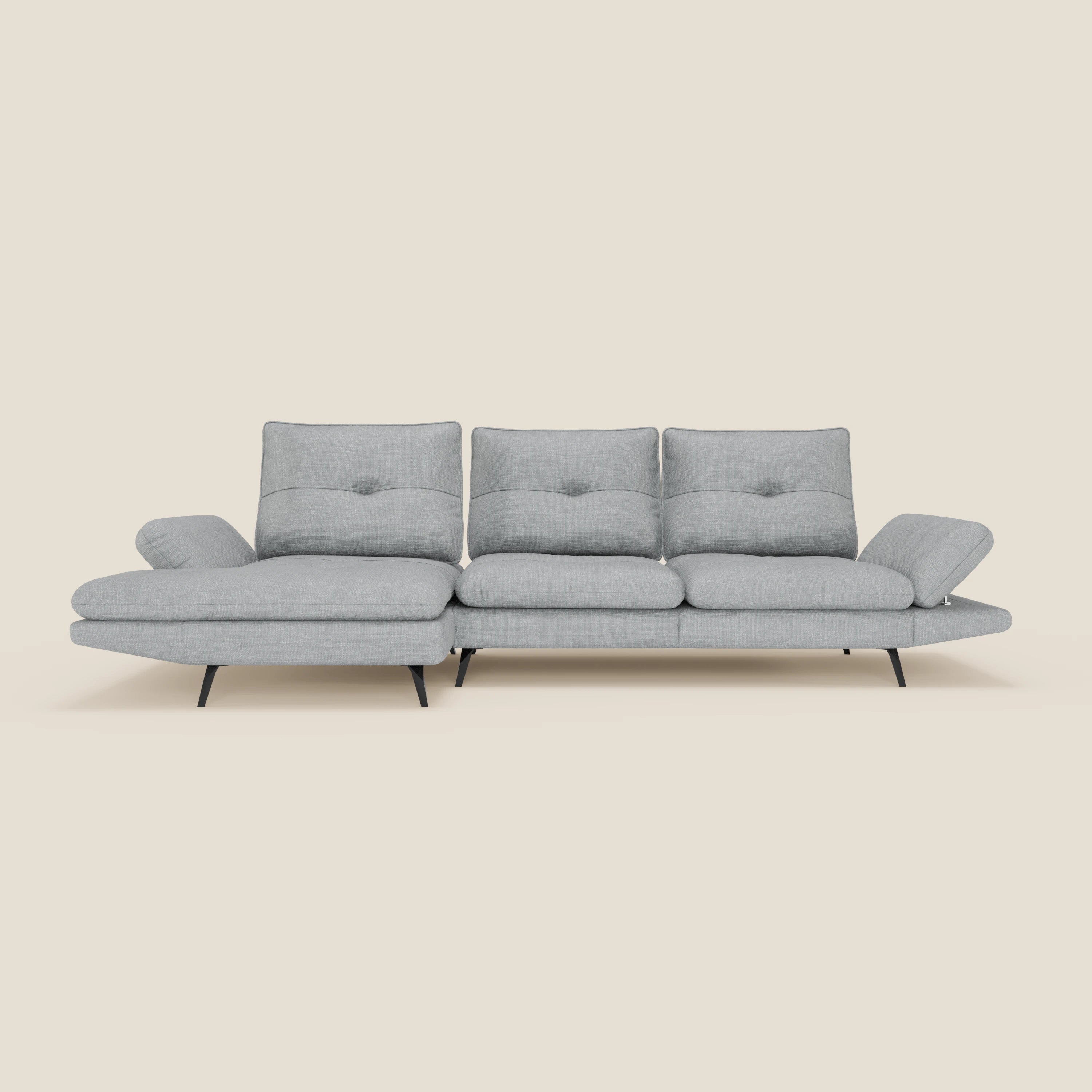 L'Ardex Divano con penisola di Divani.Store in tessuto impermeabile T06 ghiaccio è caratterizzato da tre schienali trapuntati, braccioli regolabili, gambe affusolate nere e chaise longue sinistra, su sfondo beige tinta unita.
