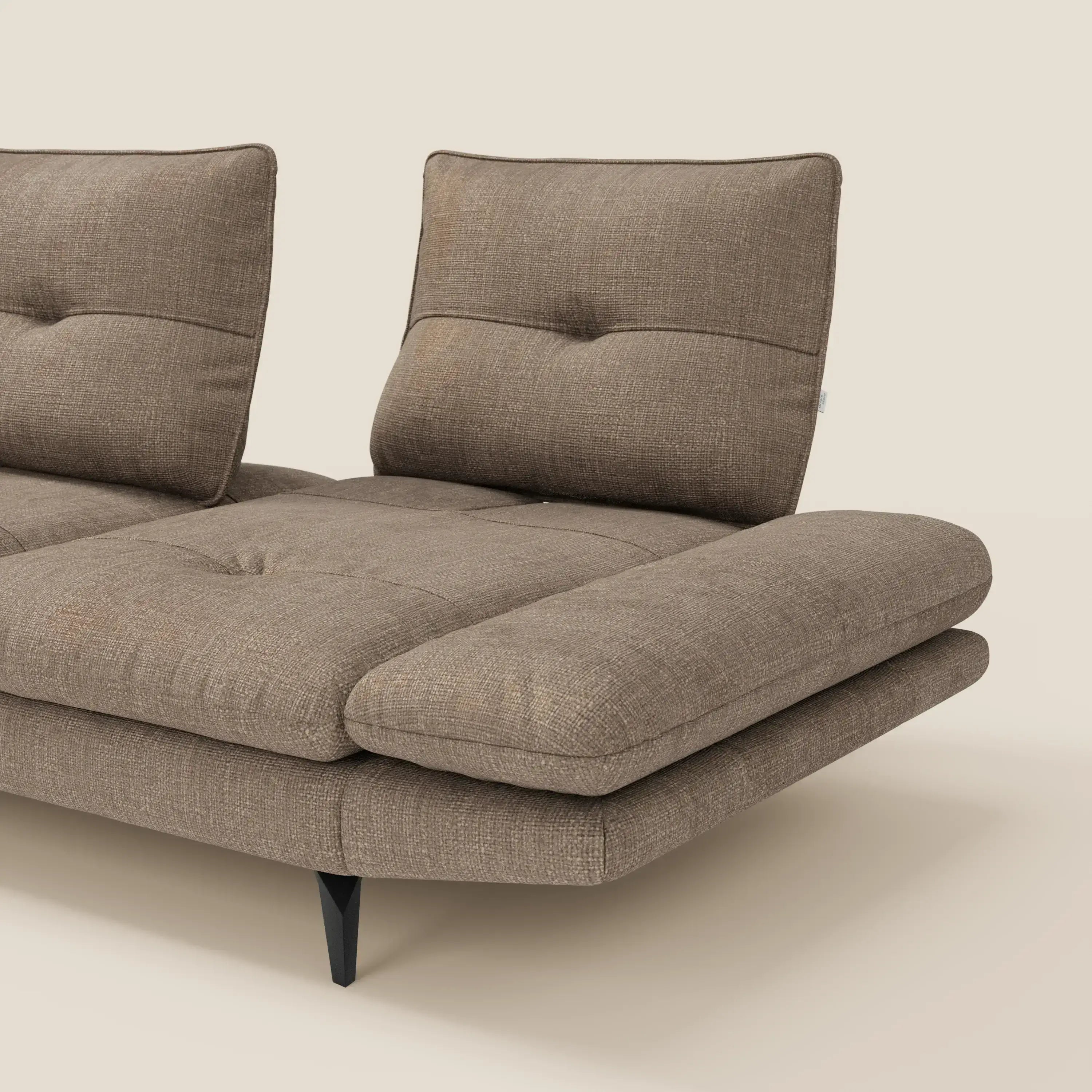 Il divano Ardex Divano con penisola di Divani.Store è caratterizzato da un elegante tessuto impermeabile marrone T06, due schienali verticali separati, ampi cuscini di seduta in tessuto felpato, sottili bottoni e gambe angolate nere. Solo una parte è visibile su uno sfondo beige.