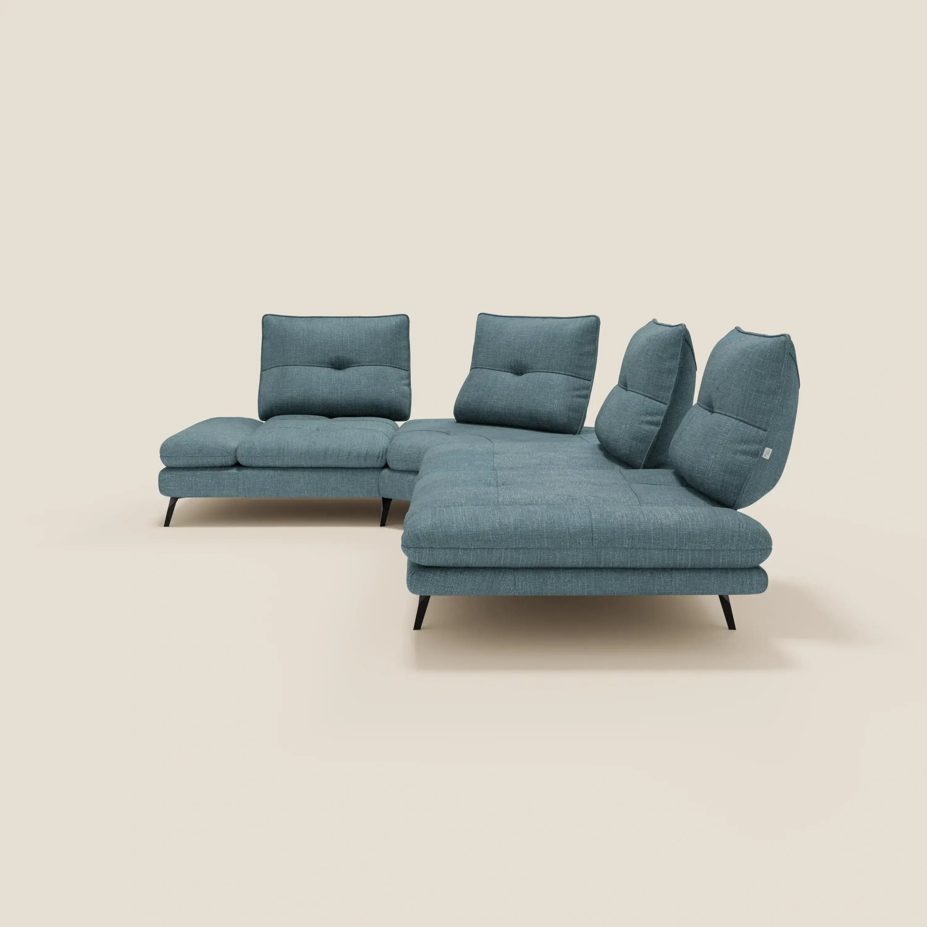 Ardex Divano Angolare di Divani.Store è caratterizzato da schienali traslanti, un bracciolo regolabile e un elegante tessuto impermeabile T06 azzurro; i cuscini trapuntati e le sottili gambe nere creano un look moderno su uno sfondo bianco sporco.