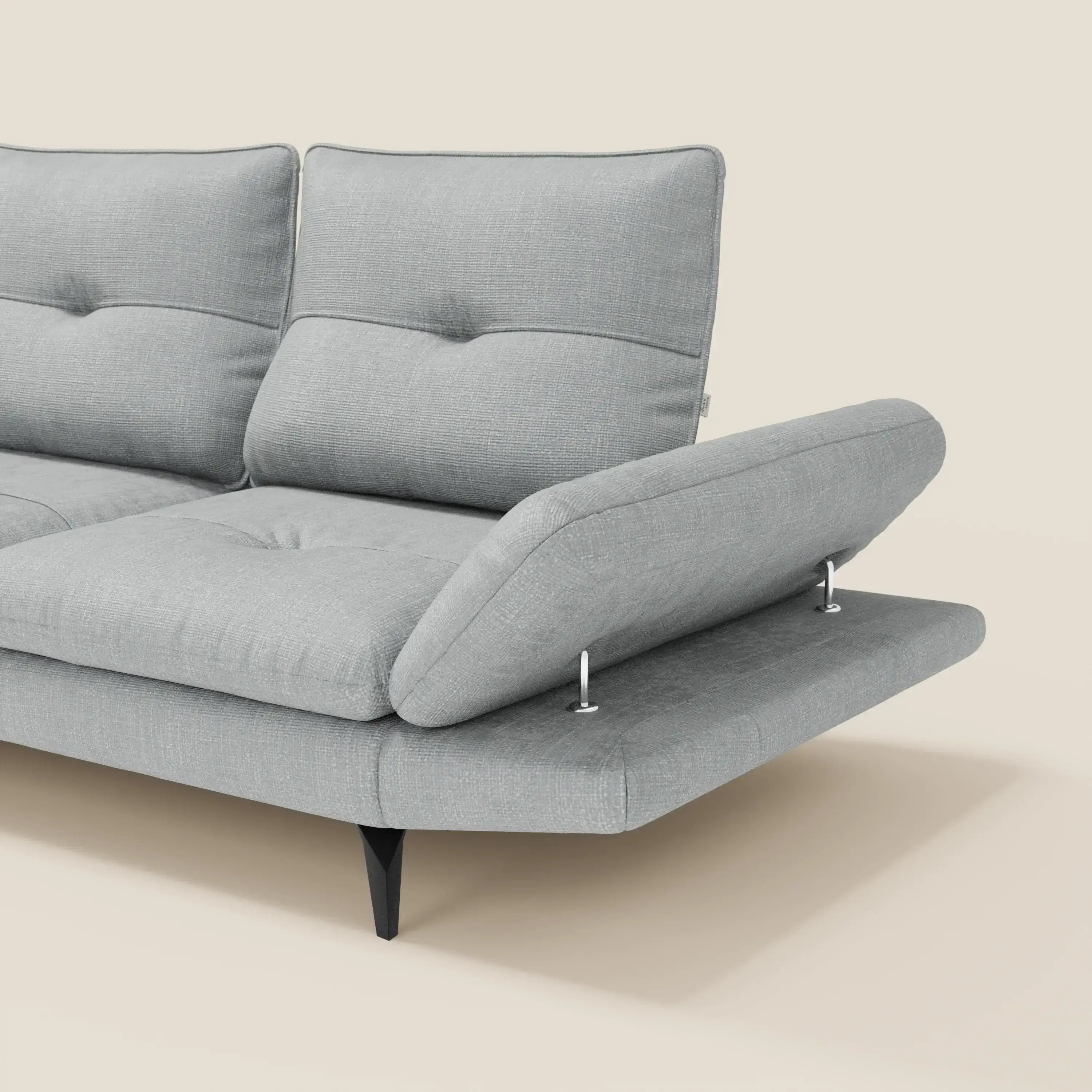 Ardex Divano Angolare di Divani.Store è presentato in tessuto impermeabile T06 ghiaccio, con schienale scorrevole e bracciolo regolabile su cerniere metalliche, gambe affusolate nere su sfondo beige.