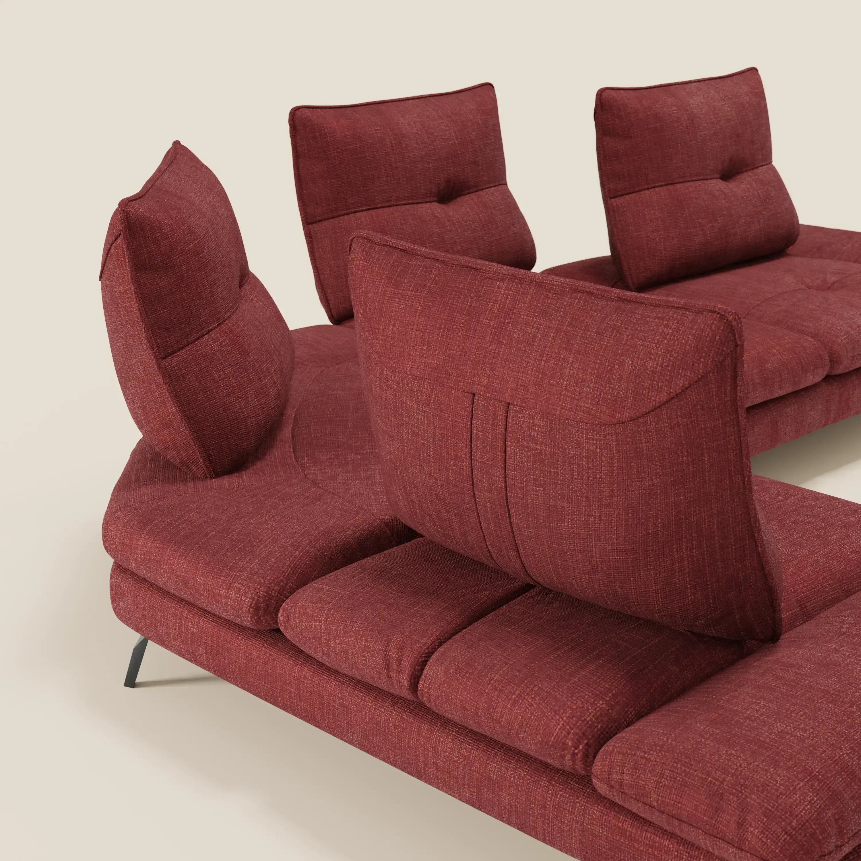 Ardex Divano Angolare di Divani.Store è caratterizzato da schienali traslanti, bracciolo regolabile ed elegante tessuto impermeabile rosso T06. Poggiato su sottili gambe in metallo nero con sottili dettagli capitonné, spicca su uno sfondo beige chiaro.