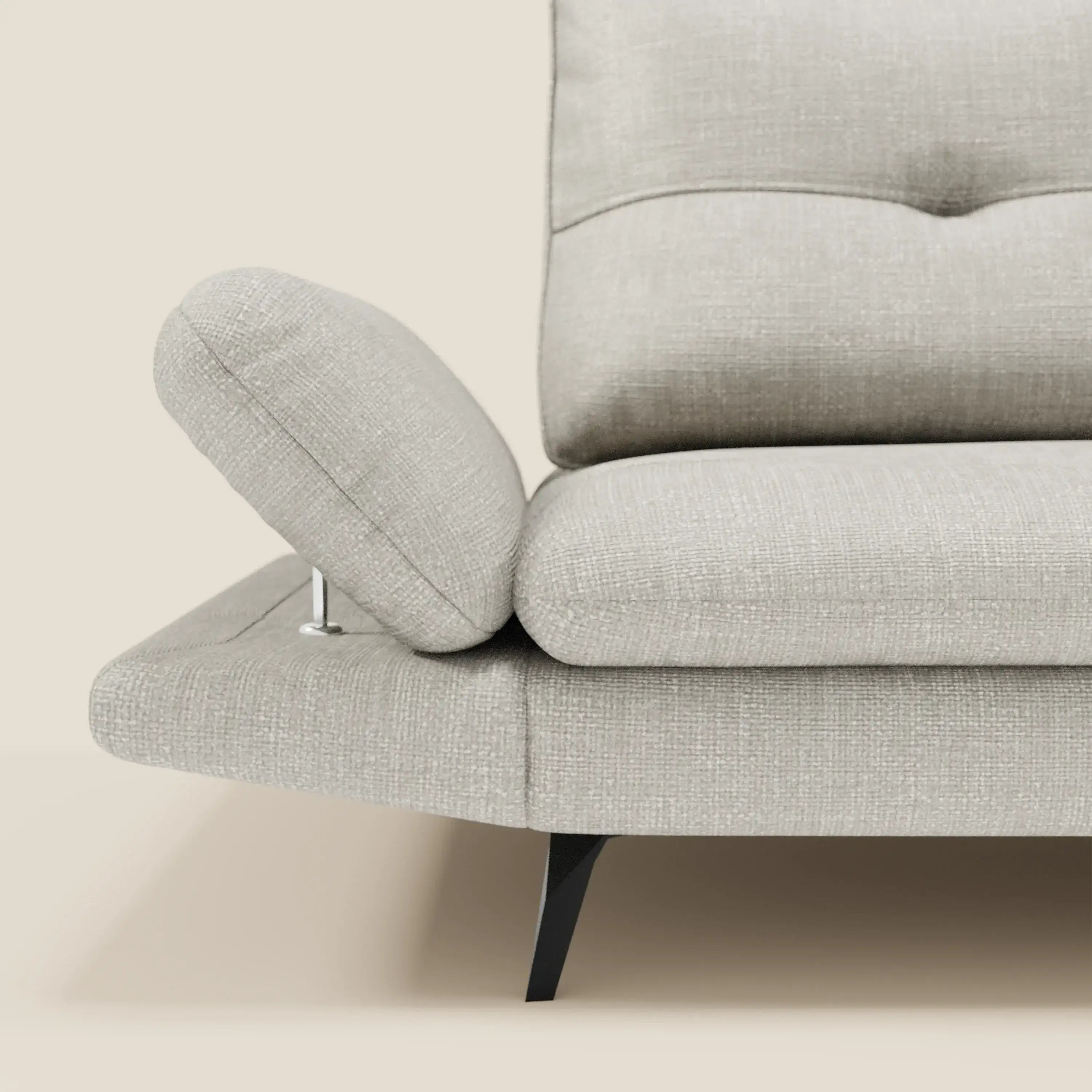 Un primo piano di Ardex Divano 3 posti di Divani.Store in T06 grigio chiaro impermeabile, mostra i braccioli regolabili, le gambe angolari nere e il tessuto testurizzato che spicca su uno sfondo beige.